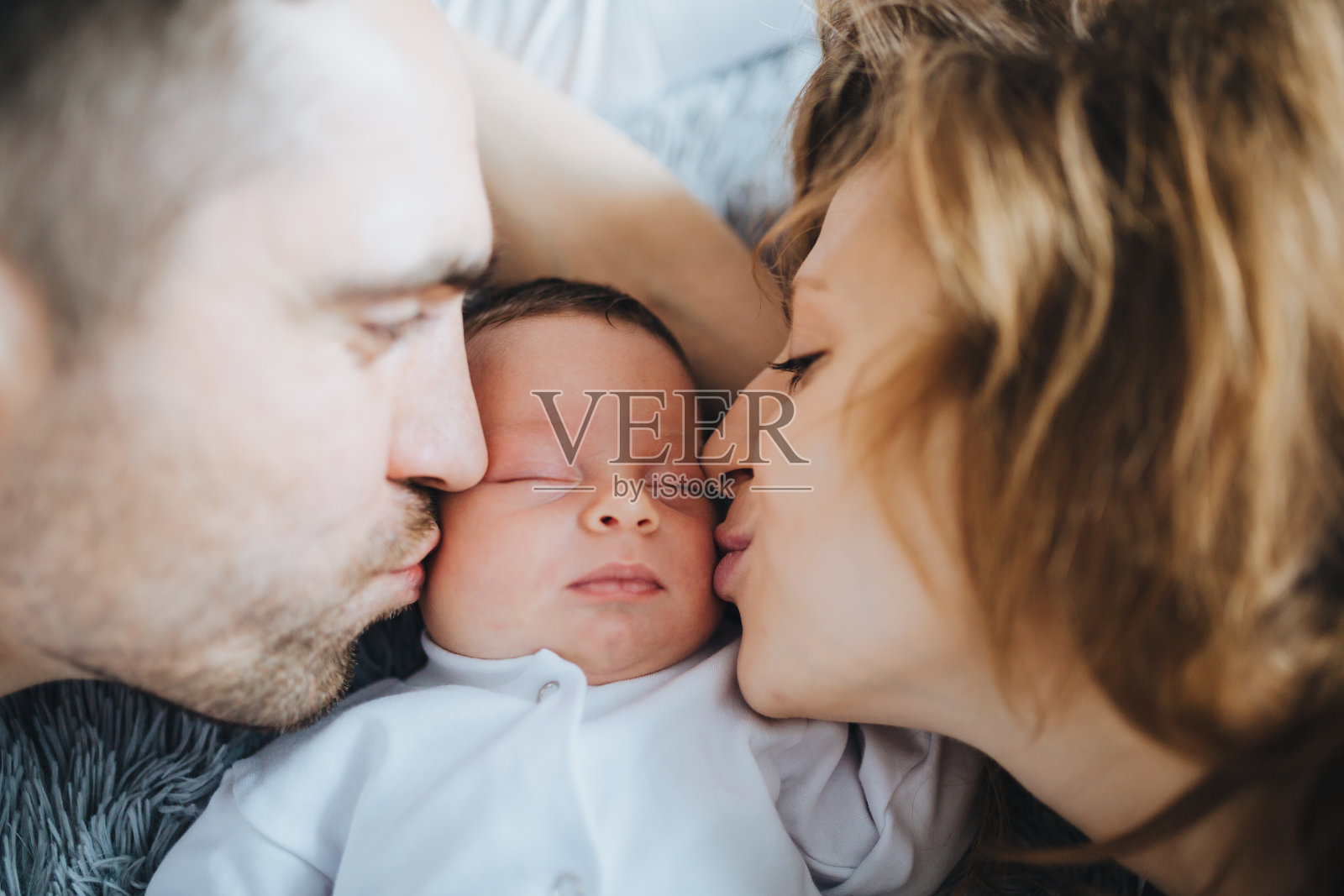 慈爱的父母亲吻着熟睡的新生婴儿照片摄影图片