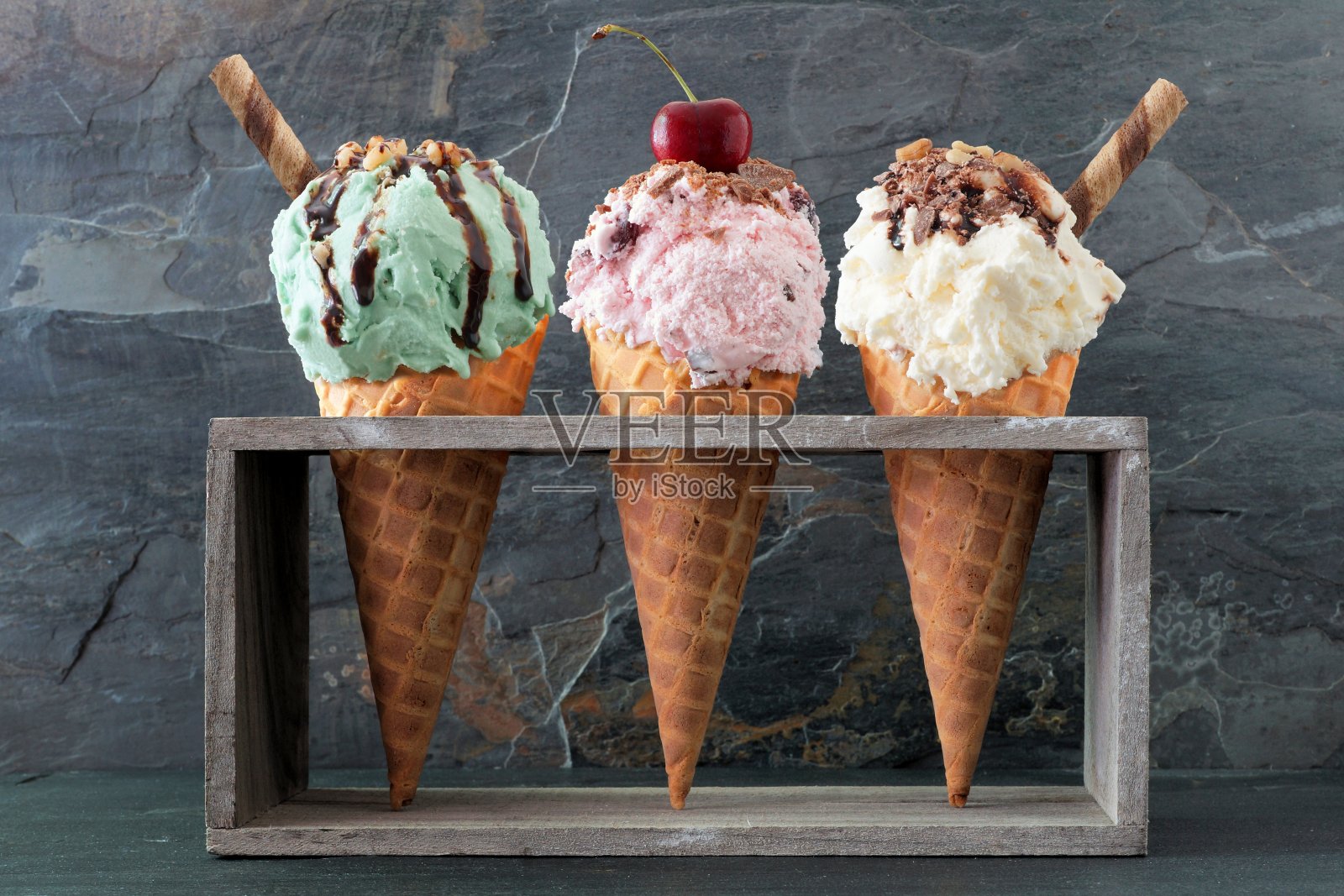 开心果、樱桃和香草的华夫筒冰淇淋盖在石板上照片摄影图片