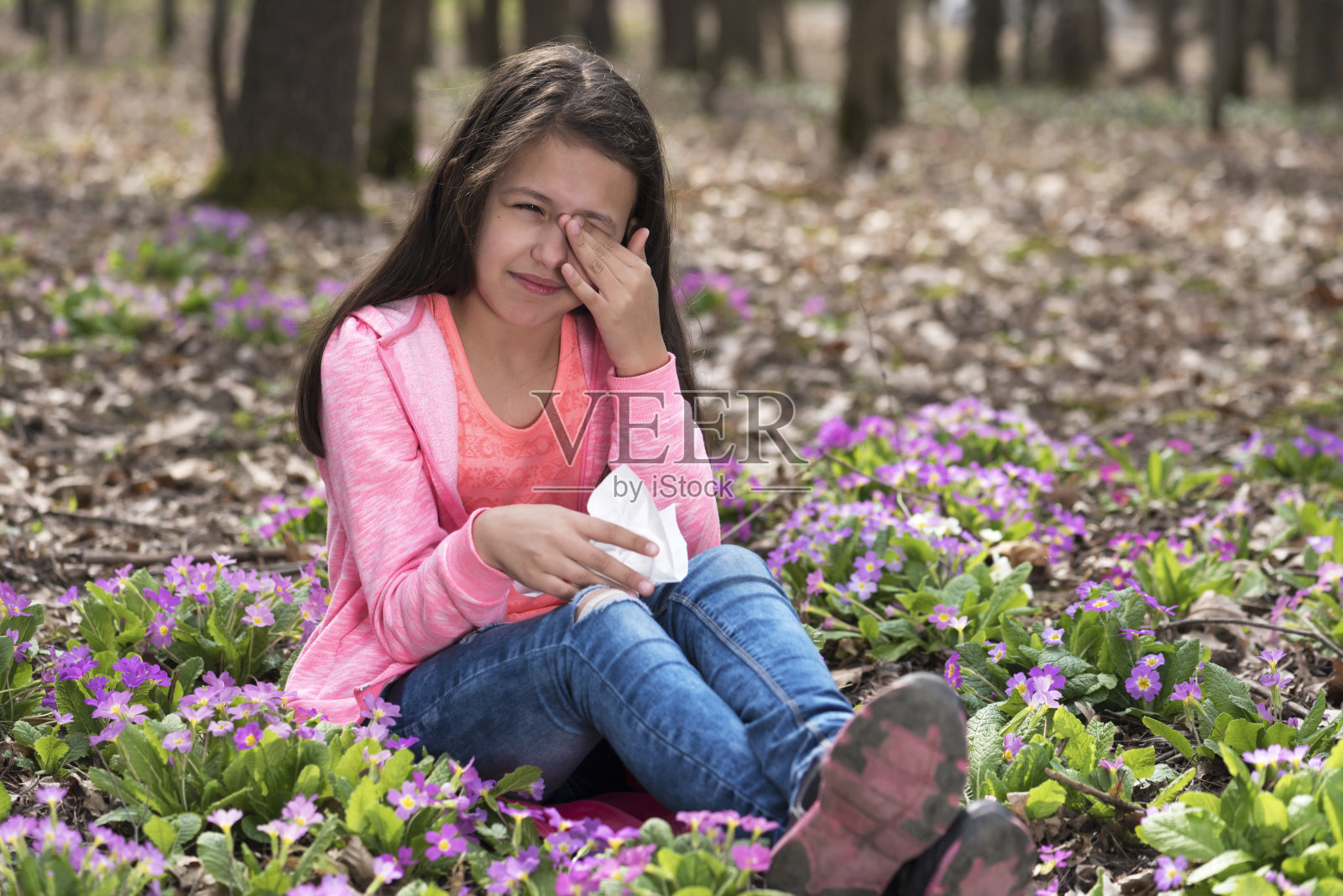 女孩坐在樱草花中，揉着眼睛照片摄影图片