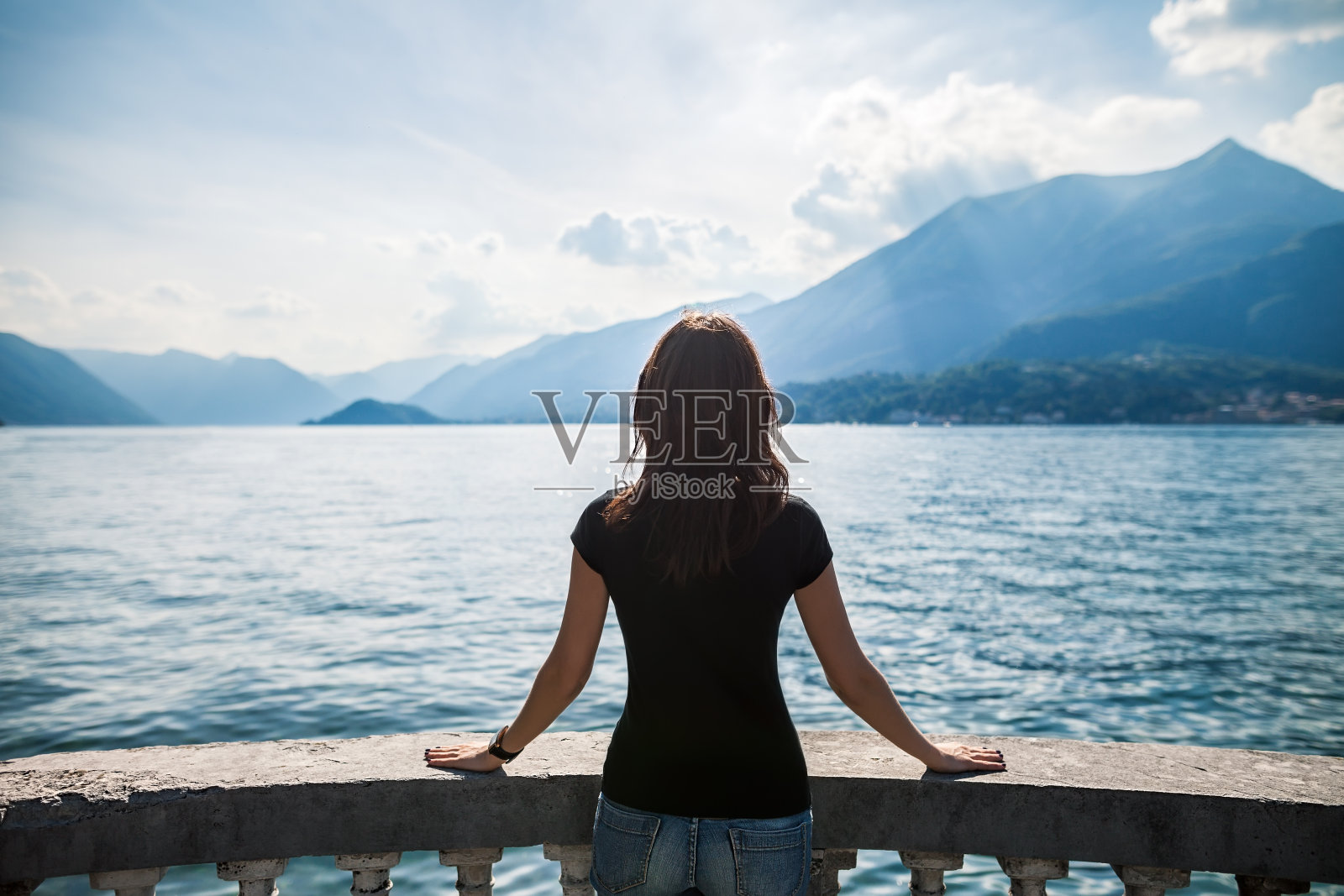 年轻女子放松在湖上的露台，意大利的后视图照片摄影图片