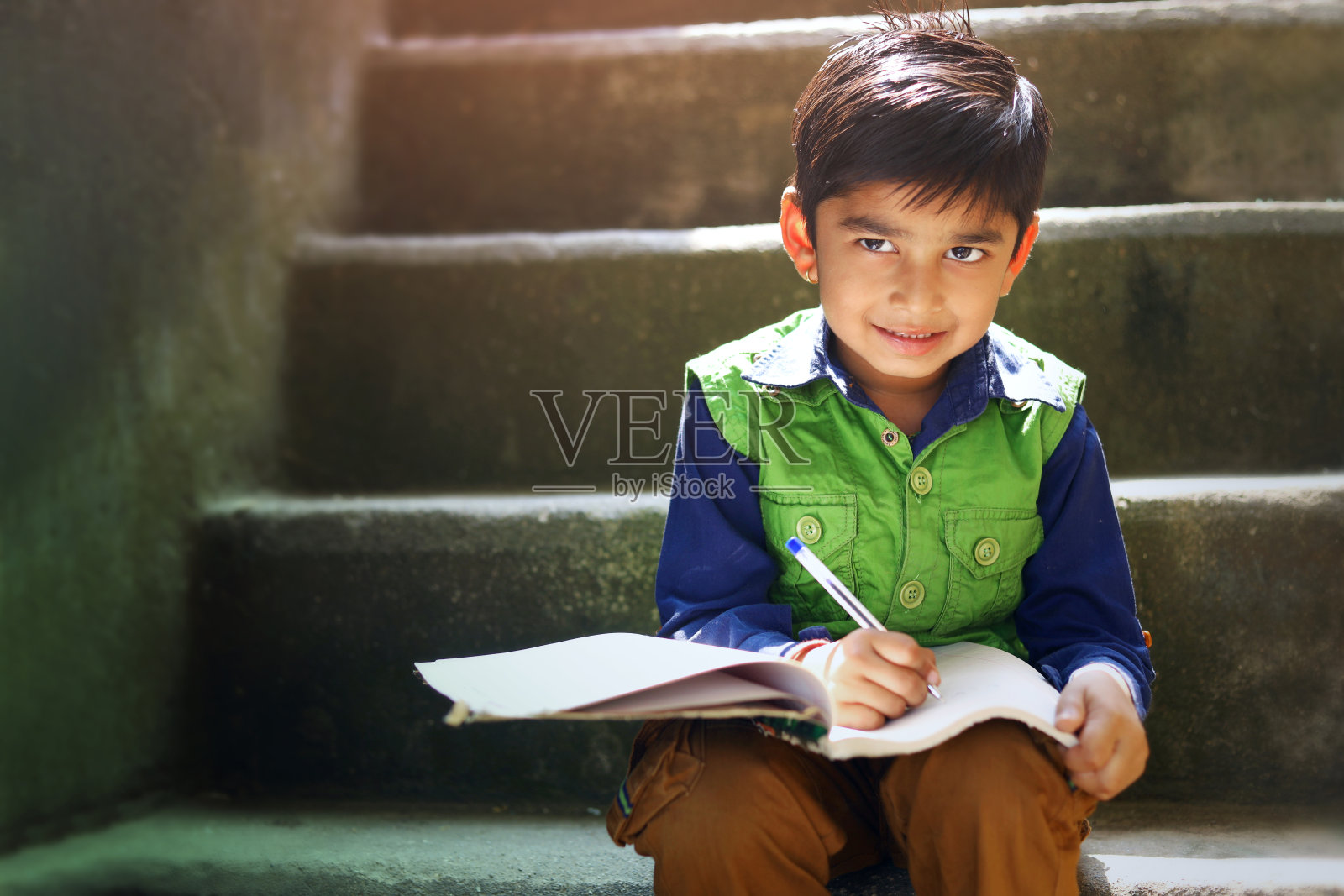 印度小孩在笔记本上写字照片摄影图片
