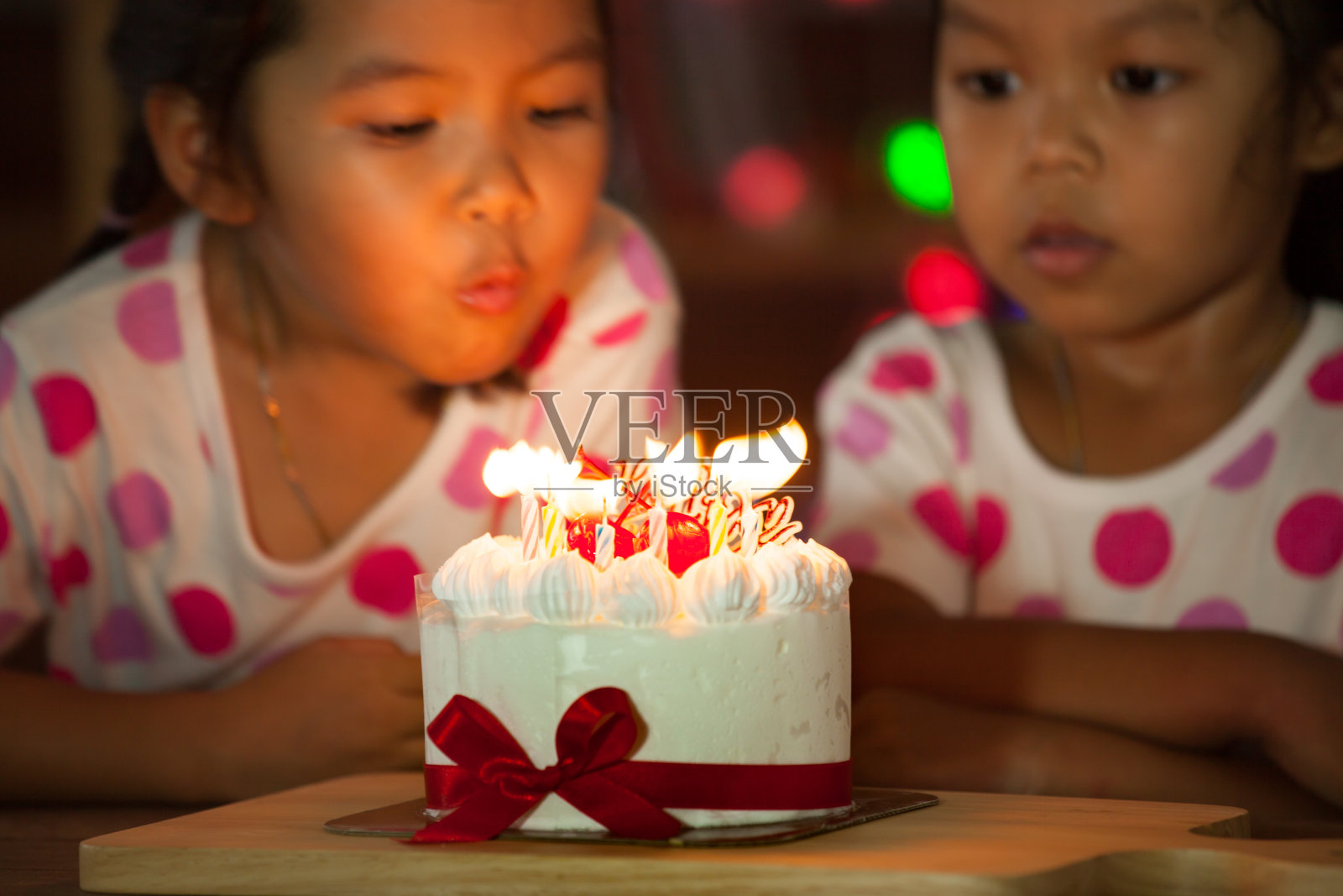 快乐的双胞胎两个亚洲小女孩庆祝生日和吹蜡烛的蛋糕照片摄影图片