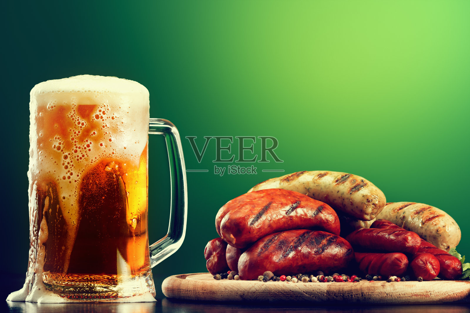 一杯绿色背景的烤香肠啤酒。慕尼黑啤酒节的饮料和食物照片摄影图片