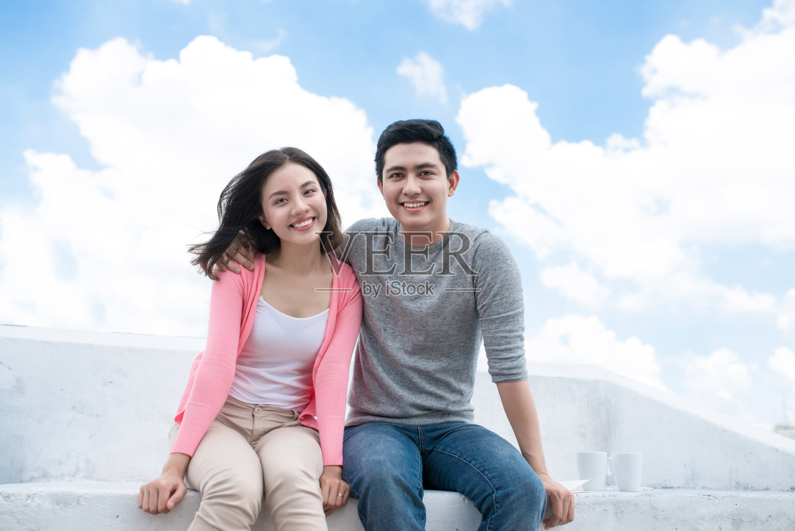 年轻的亚洲夫妇对着蓝天和云朵笑照片摄影图片