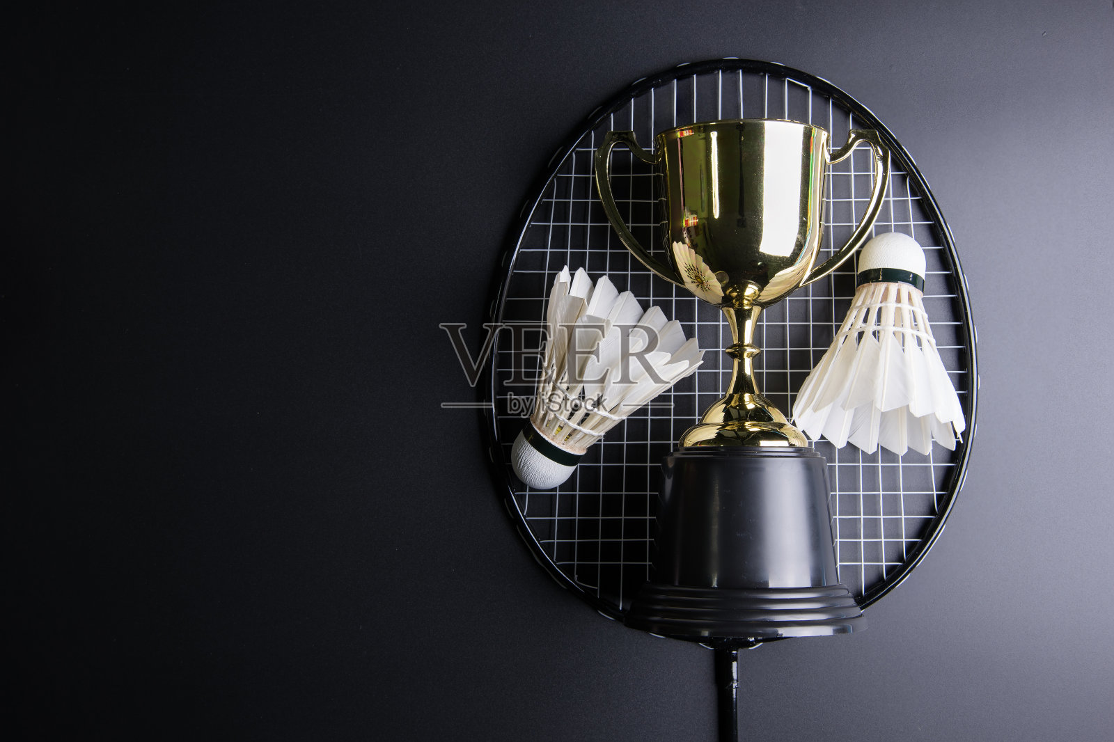 黑色背景上的金色奖杯、羽毛球和羽毛球拍。运动概念，概念赢家，复制空间图像为您的文本。照片摄影图片