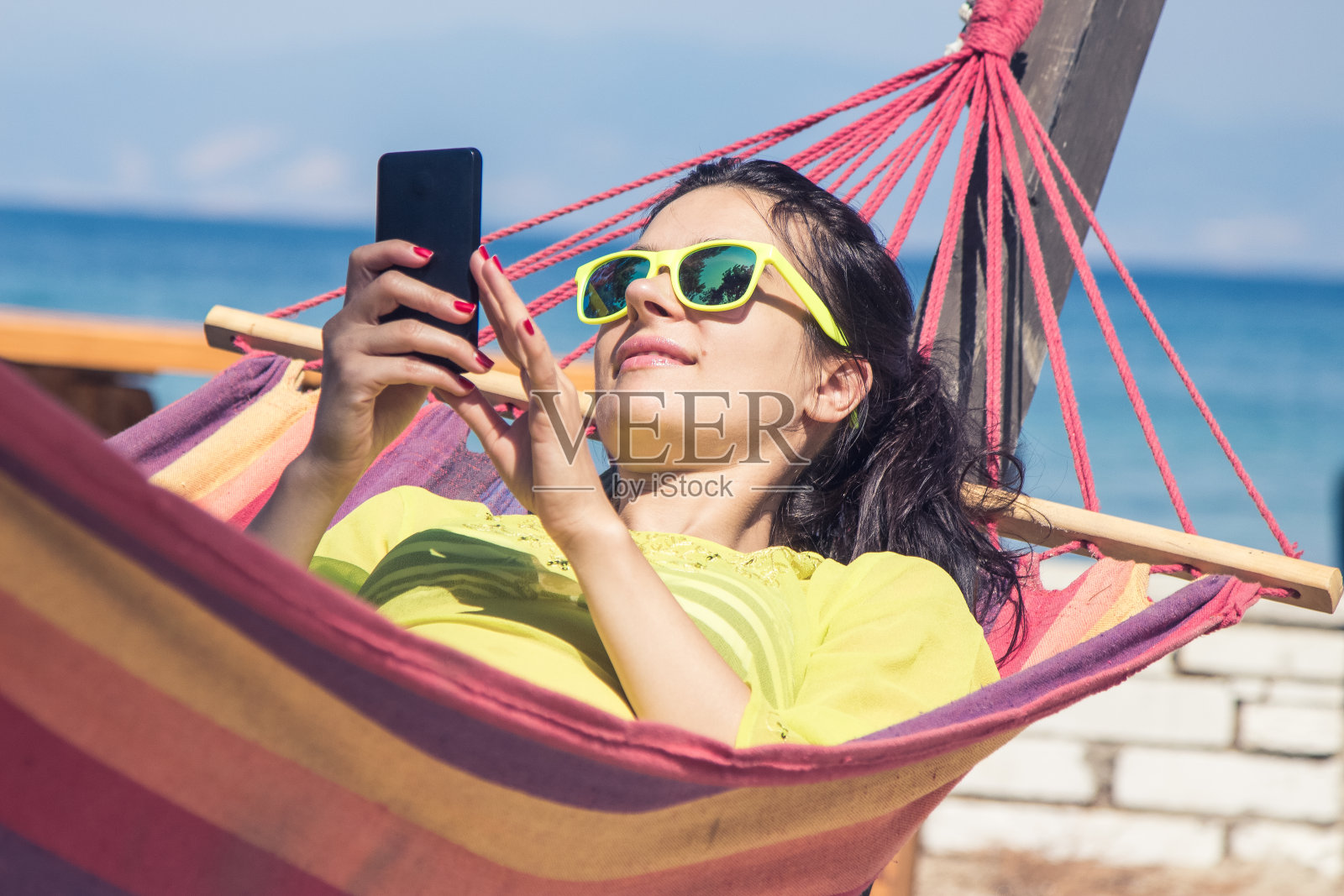 女性在吊床上使用智能手机照片摄影图片