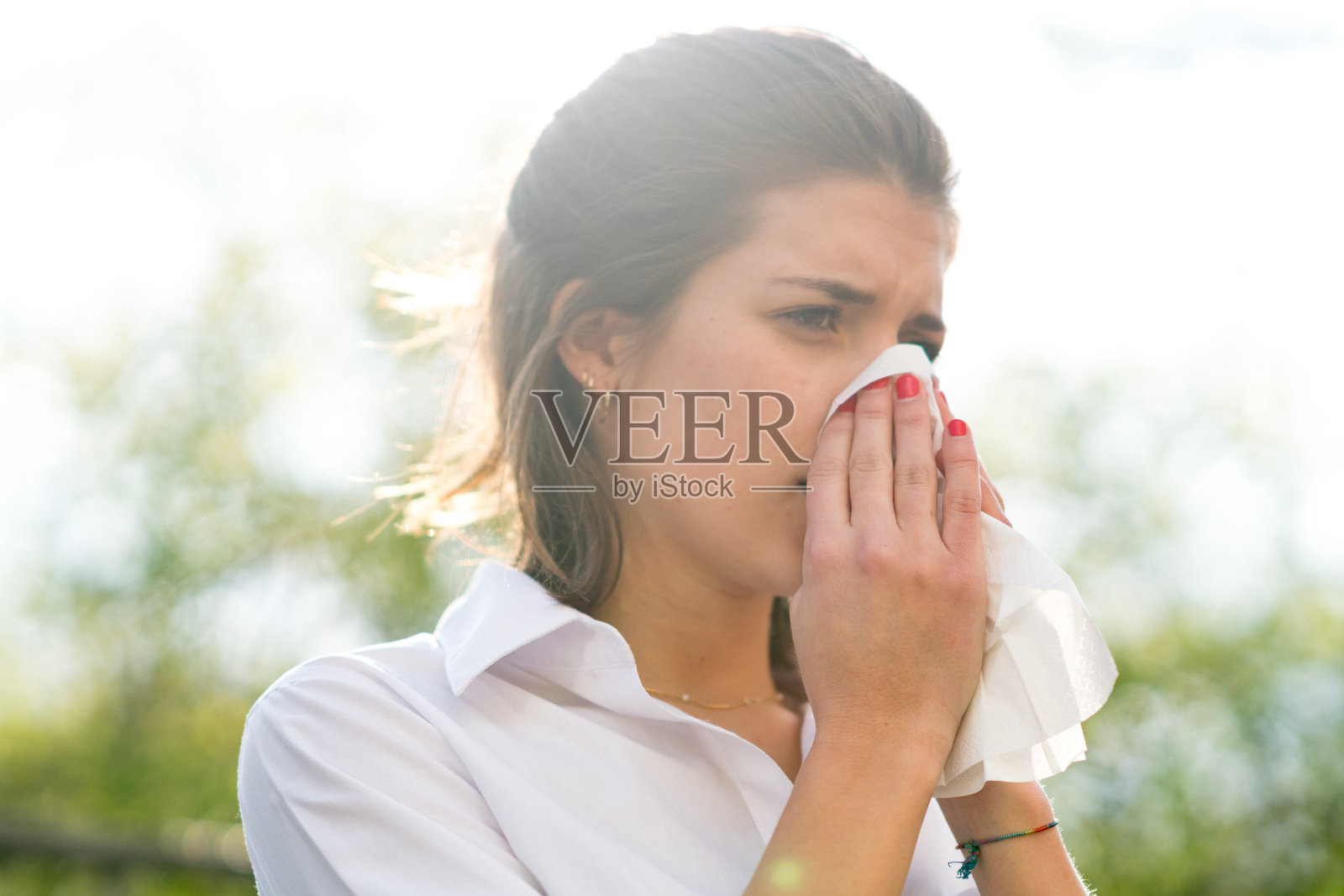 生病的女人在室外用纸巾擤鼻子照片摄影图片