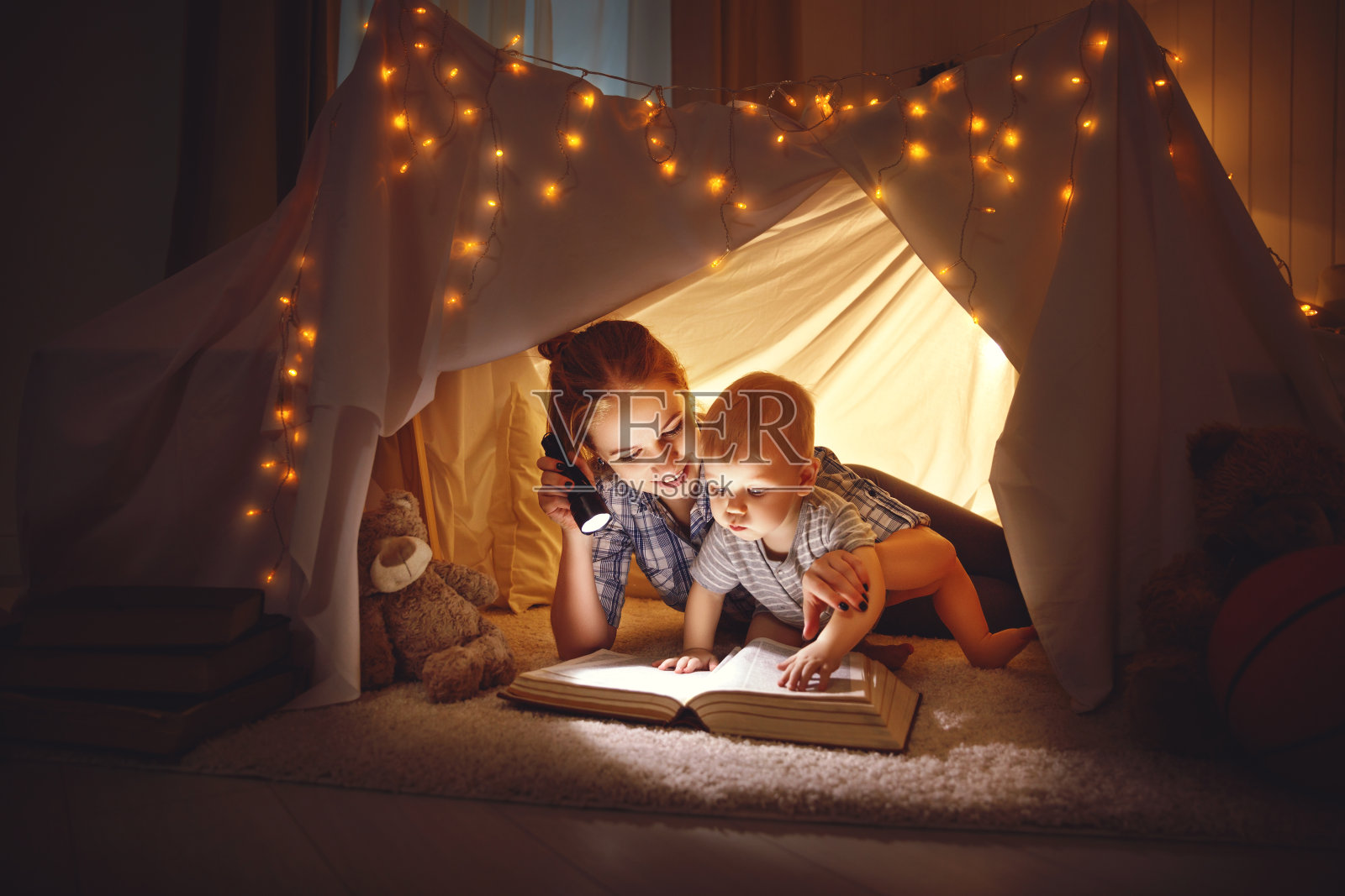 妈妈和小宝宝在睡觉前拿着一本书和手电筒照片摄影图片