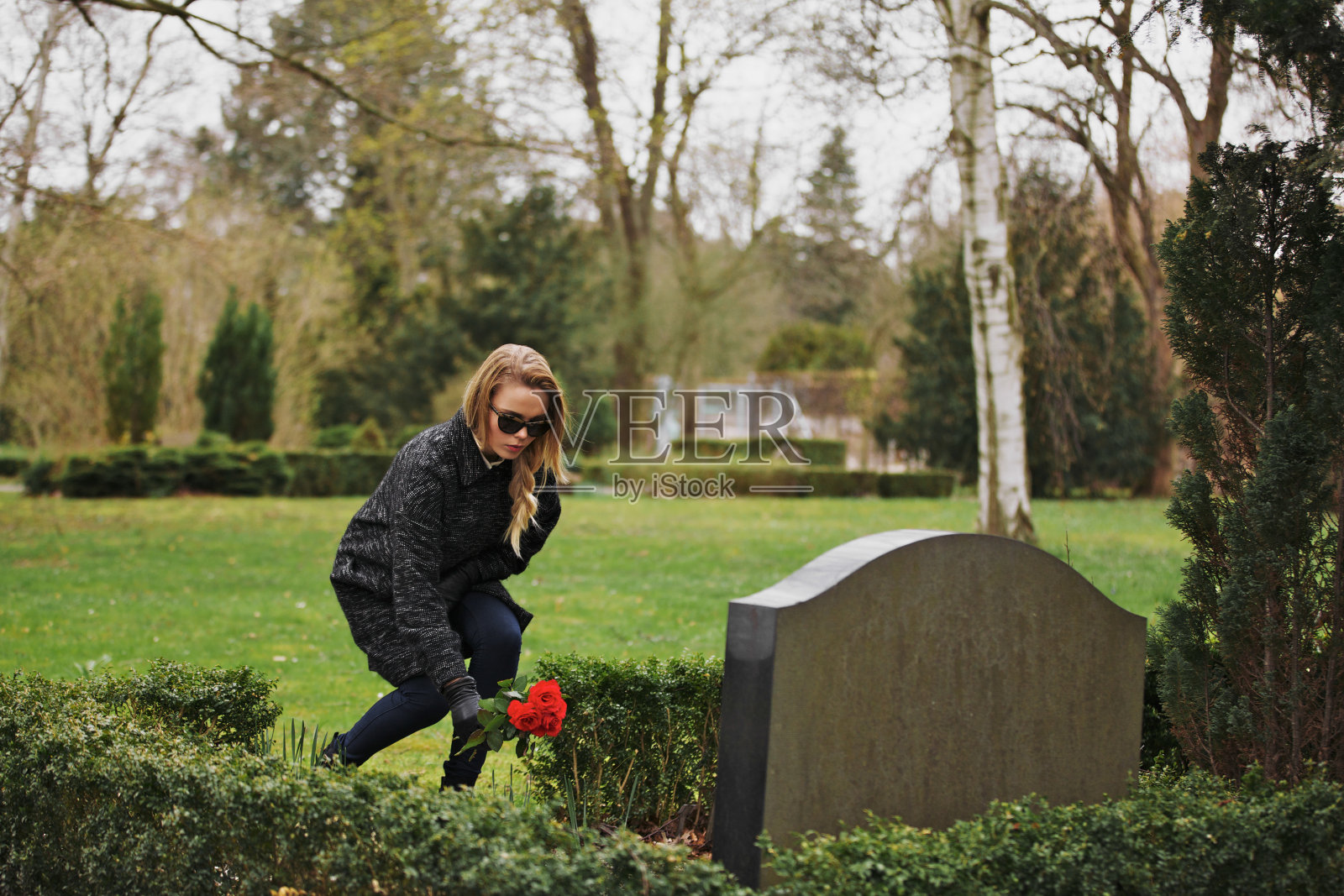 在墓地的墓碑前摆放鲜花的女人照片摄影图片