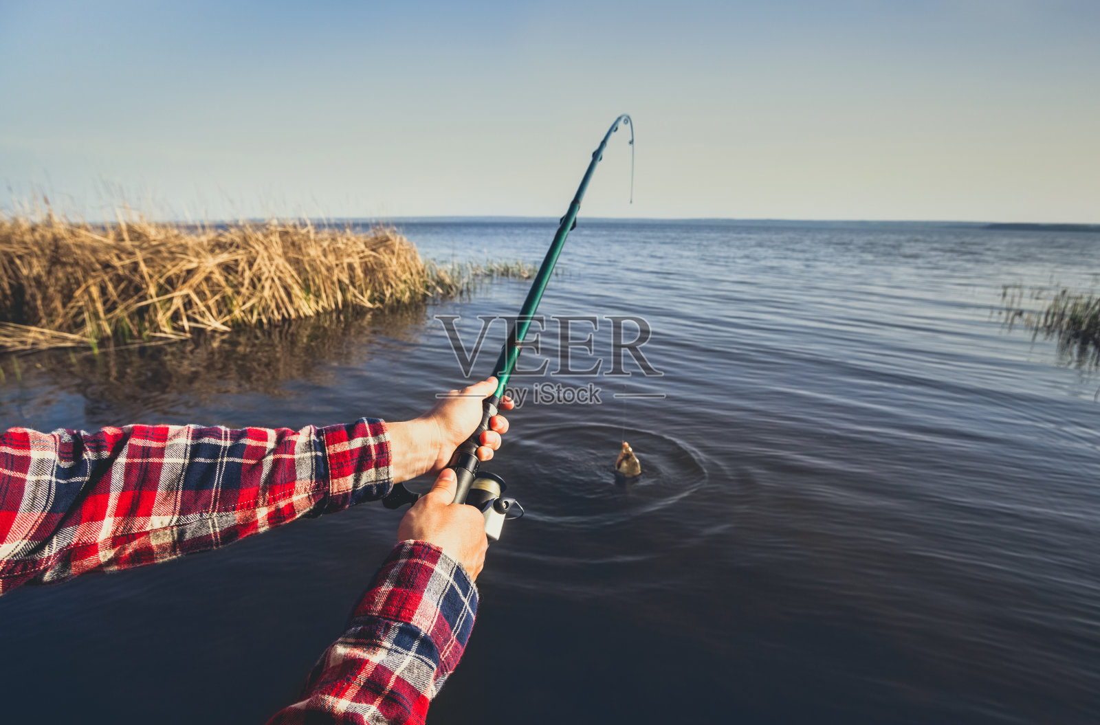 渔夫在湖岸钓鱼，双手在美丽的湖面上旋转照片摄影图片