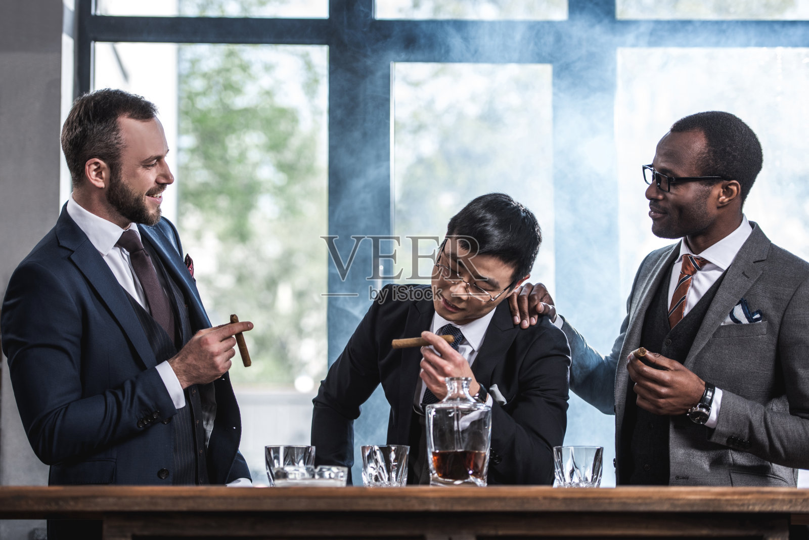 多文化商务团队花时间，抽雪茄和喝威士忌照片摄影图片