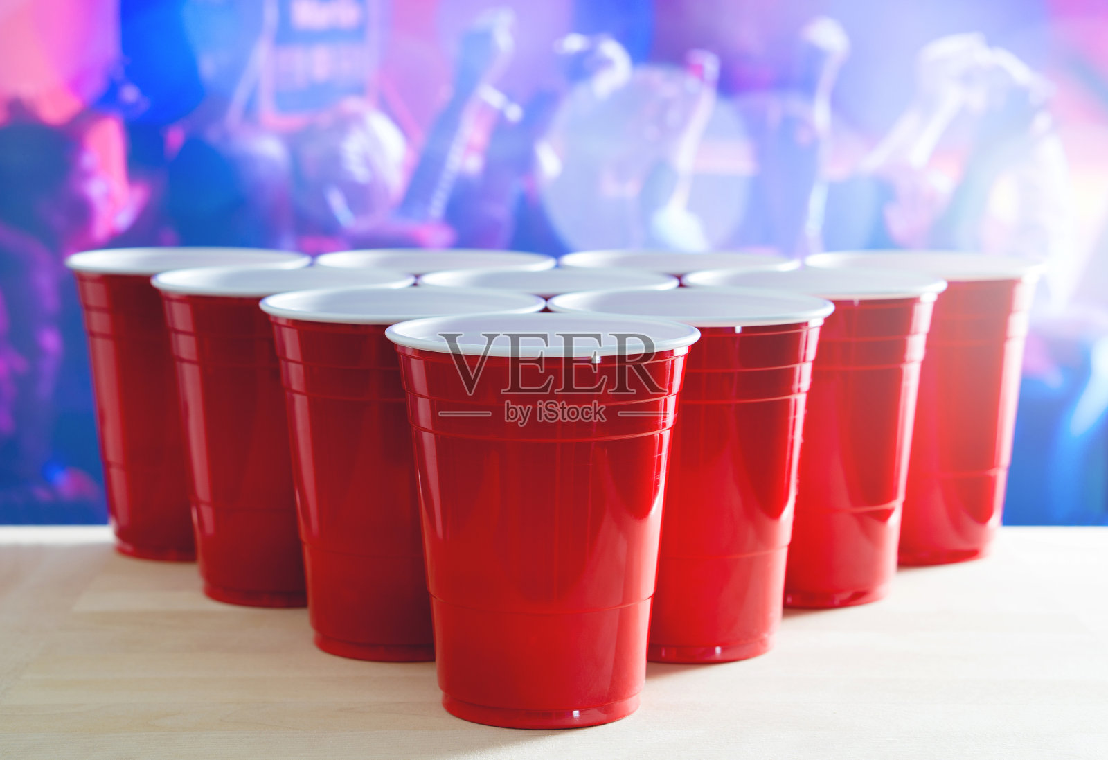 啤酒乒乓比赛布局。夜店里挤满了跳舞的人，许多红色派对杯的背景是跳舞。完美的营销和推广活动。塑料杯子放在木桌上照片摄影图片