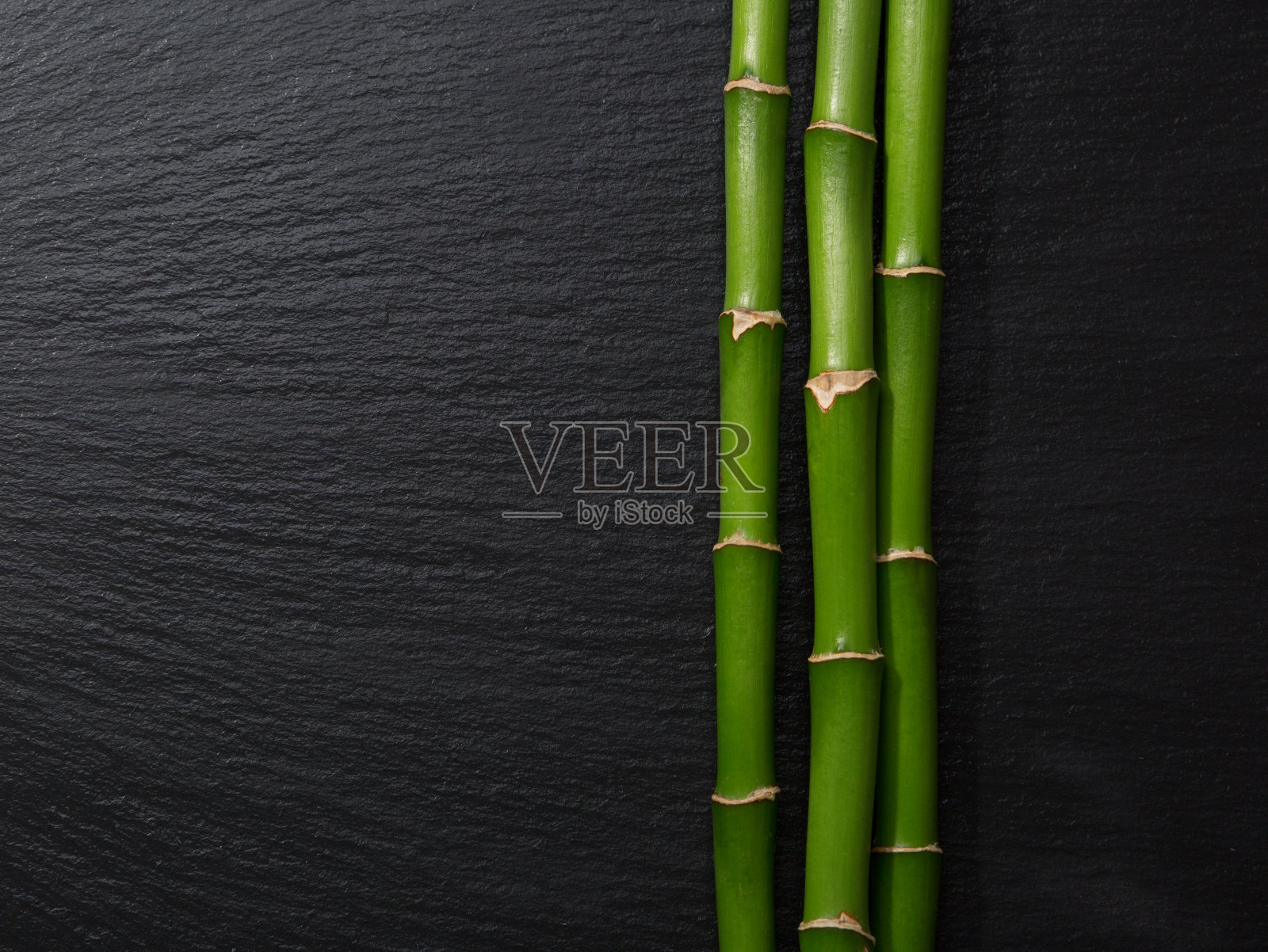 三根竹枝躺在潮湿的黑石板上照片摄影图片