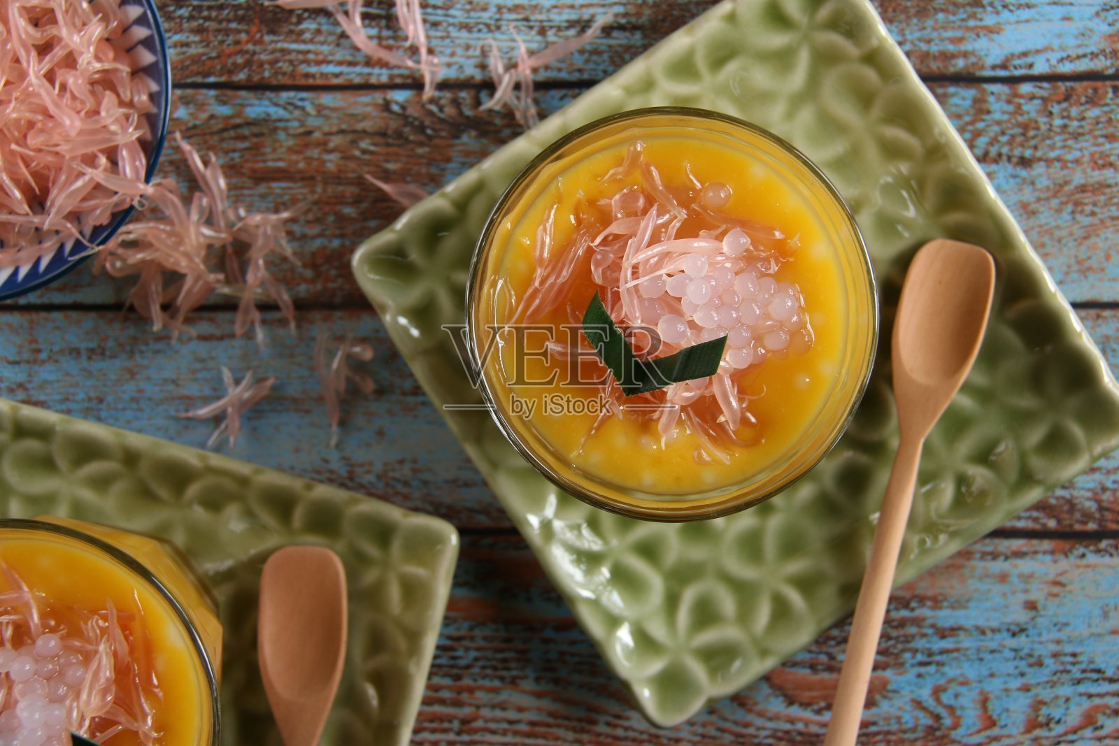 冰芒果蜜柚甜点在老式玻璃和木勺，在花压花的方形盘子照片摄影图片