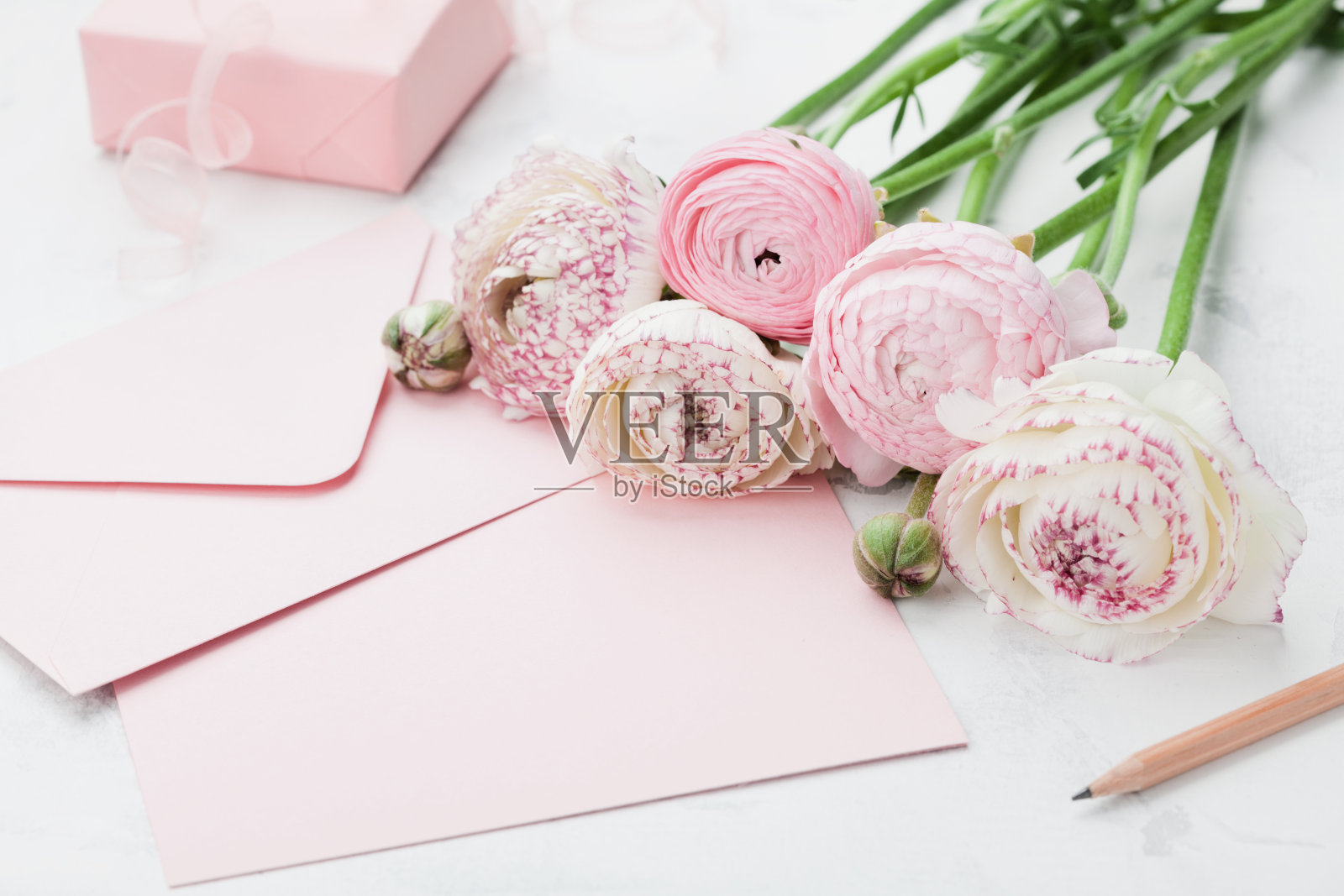 信封或信件，纸卡，礼物和粉红色的毛茛花。问候母亲或妇女节。照片摄影图片