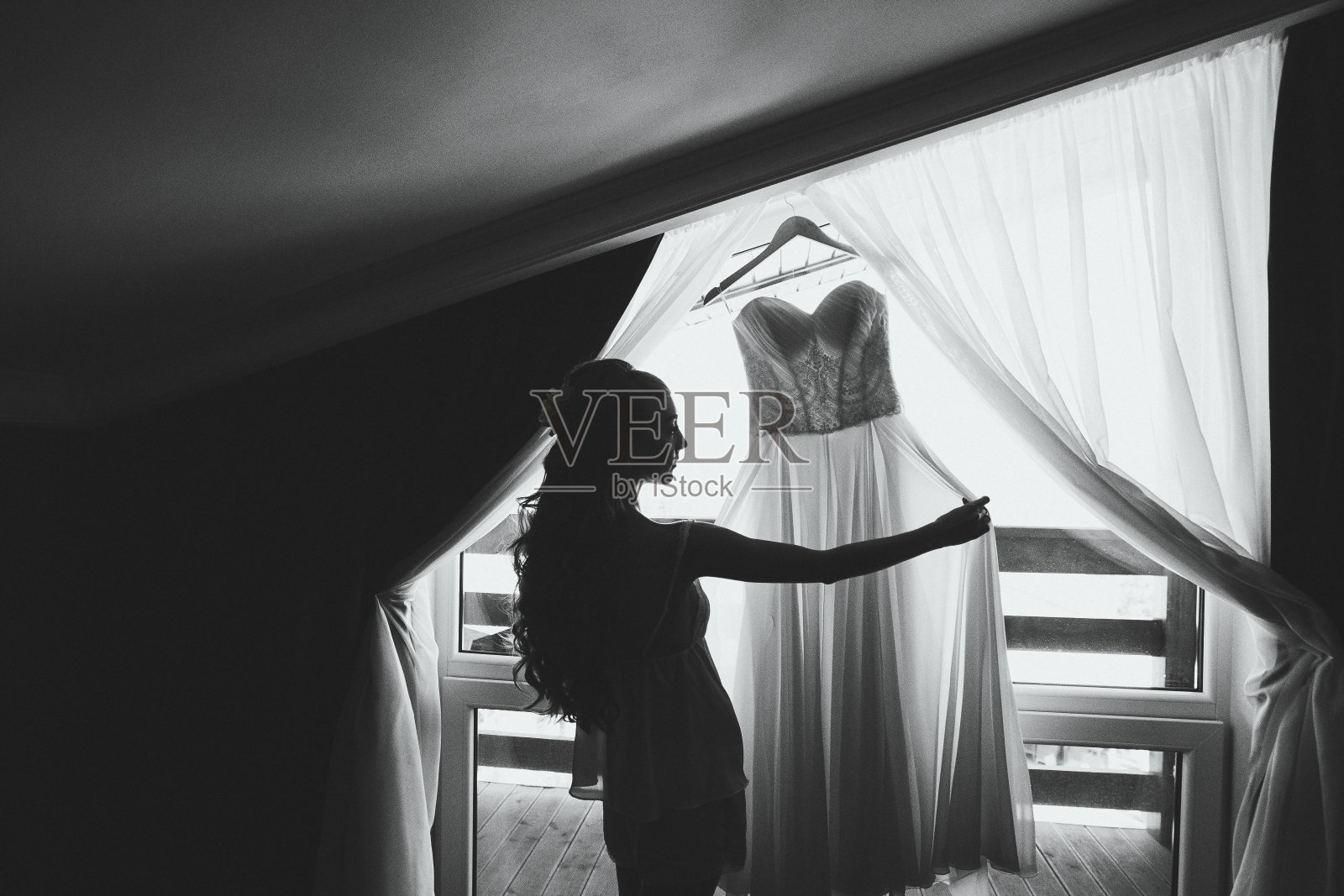 新娘的早晨，她看着挂在别墅房间里的婚纱照片摄影图片