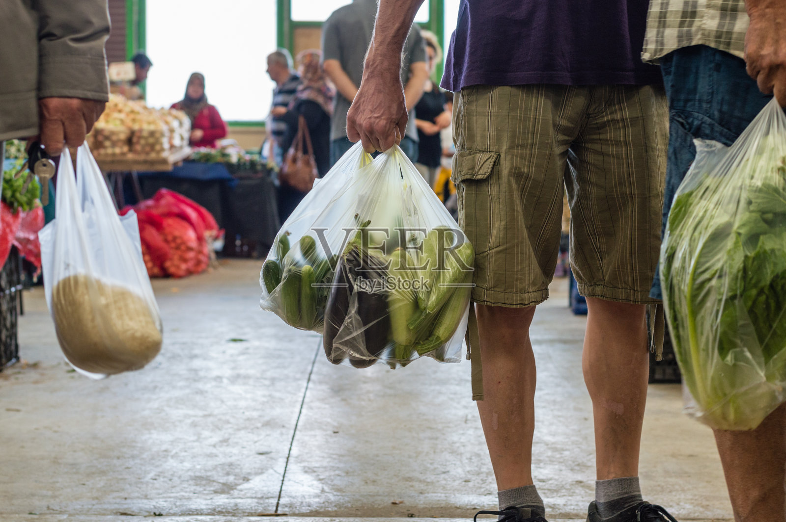男人们拿着装着蔬菜的塑料购物袋，在一个典型的土耳其蔬菜集市上照片摄影图片