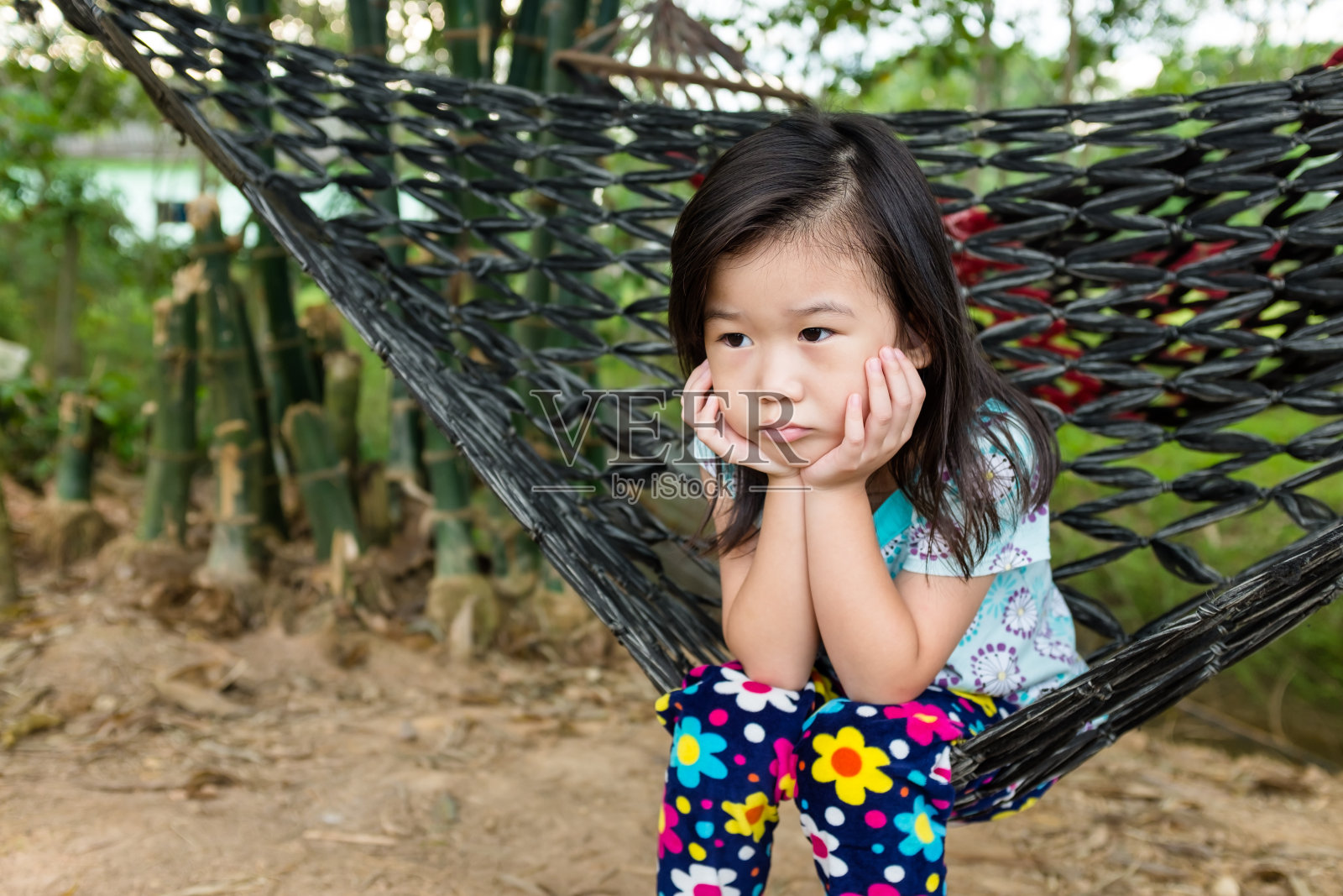 不幸的女孩独自坐在吊床上。夏日户外。照片摄影图片