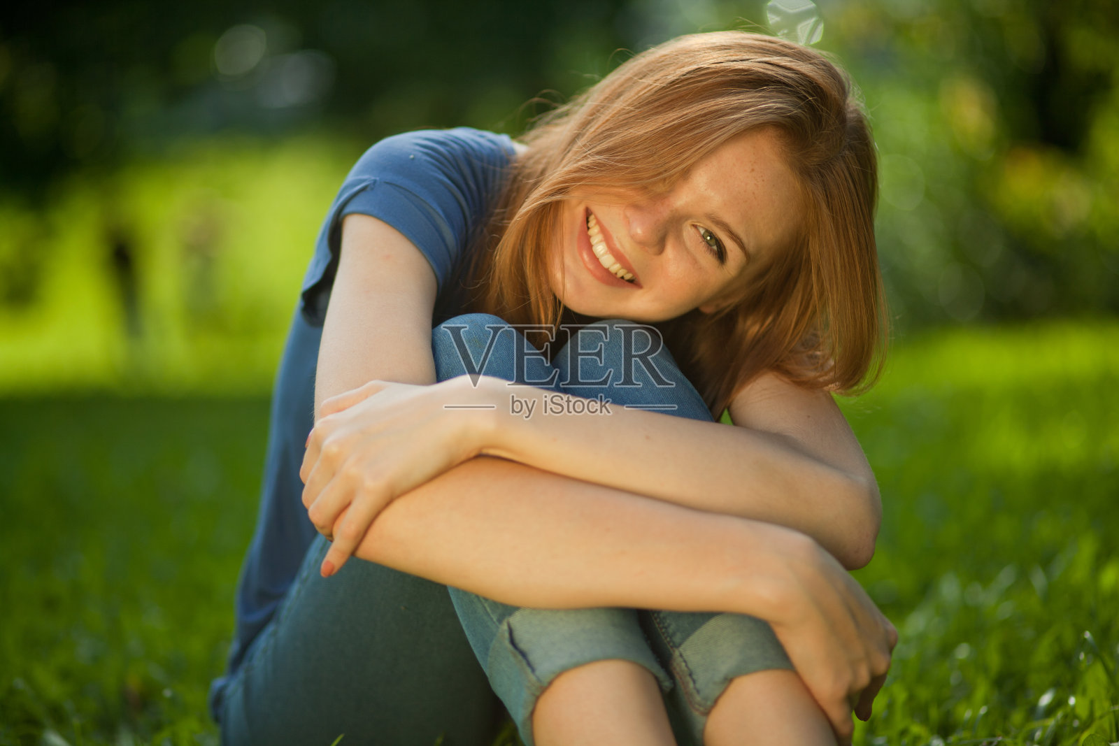 美丽的红发女孩坐在草地上照片摄影图片