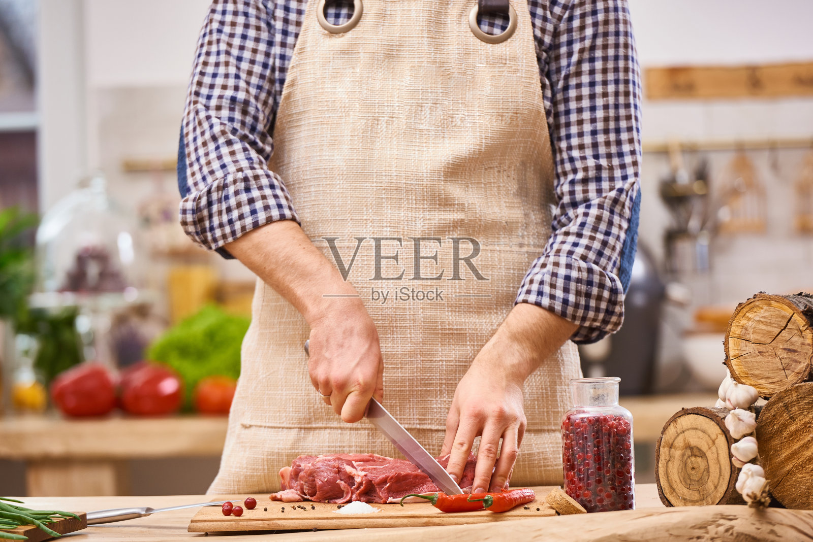 屠夫在厨房里以蔬菜为背景切猪肉、牛肉或羊肉照片摄影图片