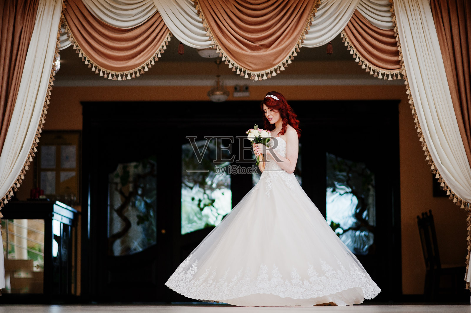 迷人的红发新娘手捧婚礼花束在盛大的婚礼大厅摆好姿势照片摄影图片