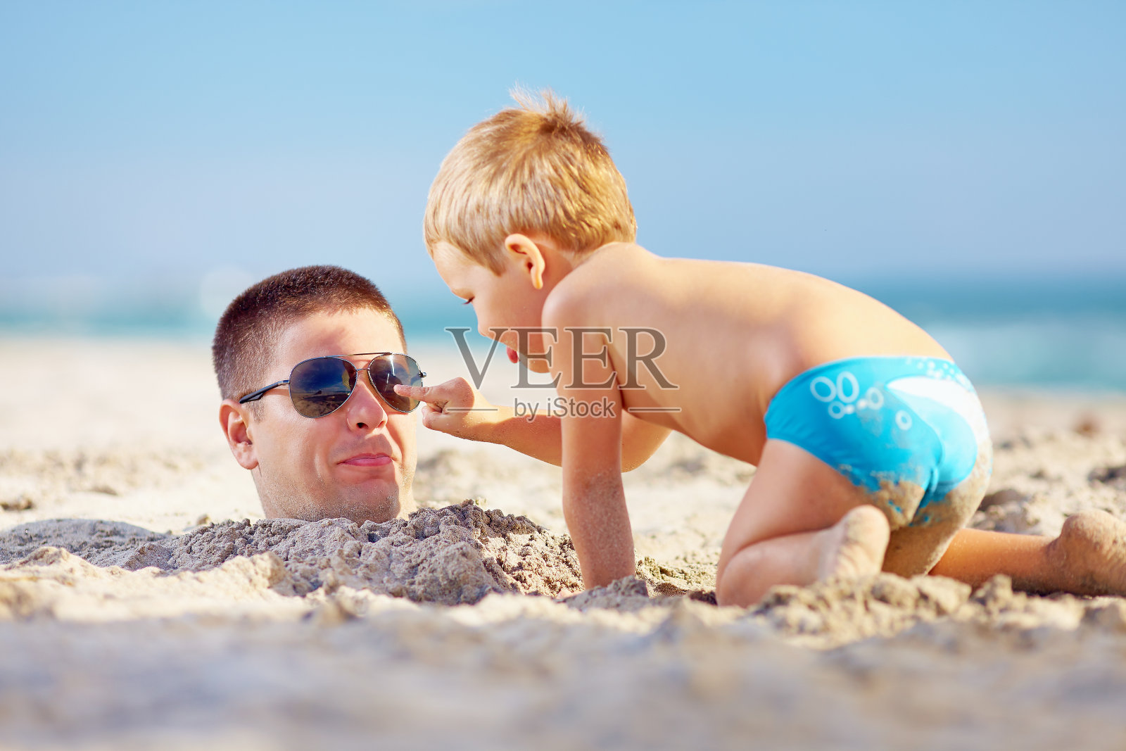 父亲和儿子在沙滩上玩沙子照片摄影图片