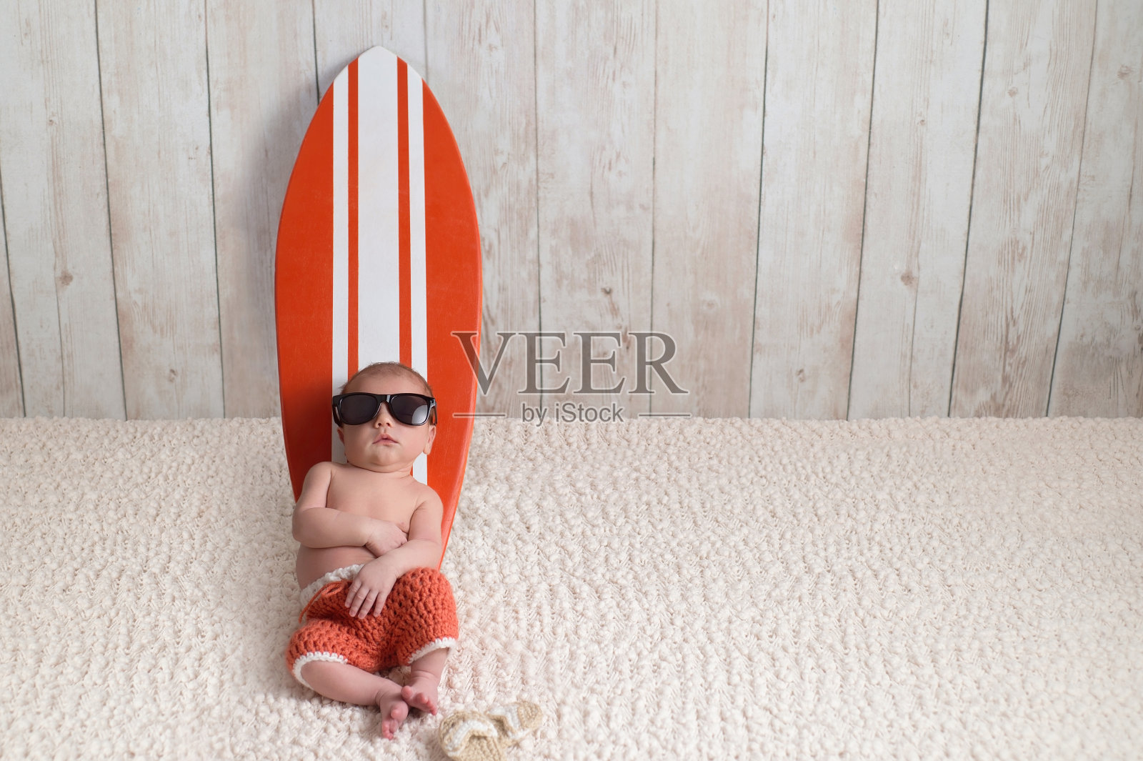 刚出生的男婴倚靠在冲浪板上照片摄影图片