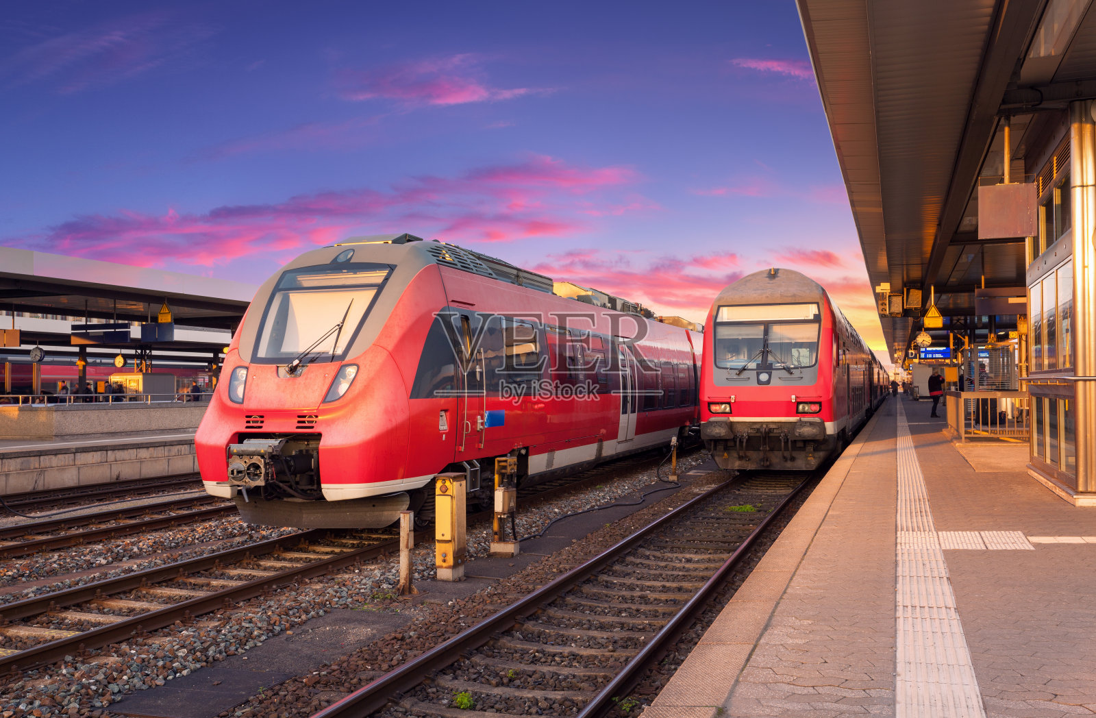 美丽的红色通勤列车在火车站和彩色天空日落在欧洲。工业景观与美丽的铁路站台和现代列车在夏季。铁路。铁路旅游照片摄影图片