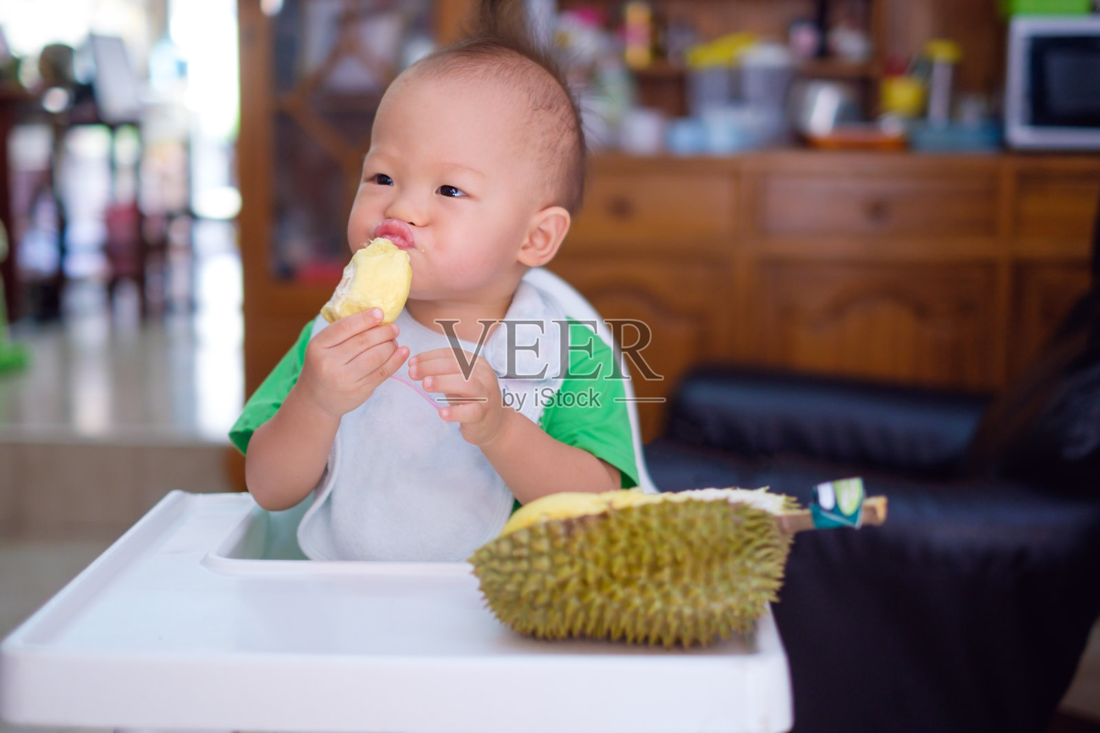 可爱有趣的亚洲小男孩在家里拿着闻和吃榴莲照片摄影图片