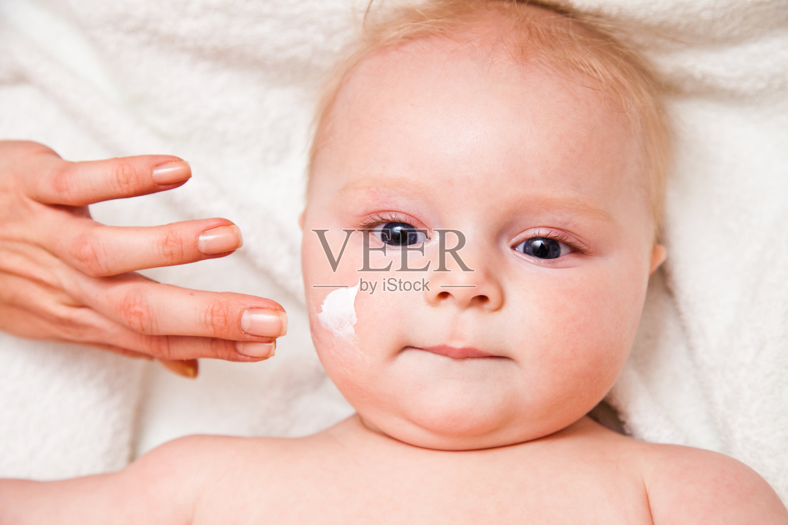 沐浴后在女婴脸上擦面霜照片摄影图片