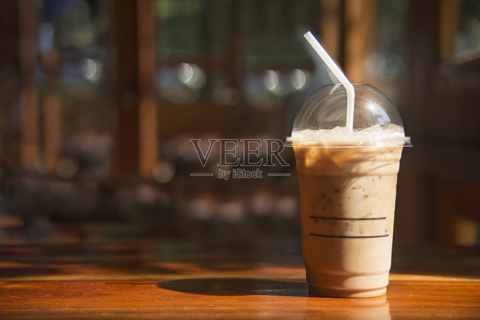 咖啡馆棕色木桌上的塑料杯里的冷咖啡。照片摄影图片