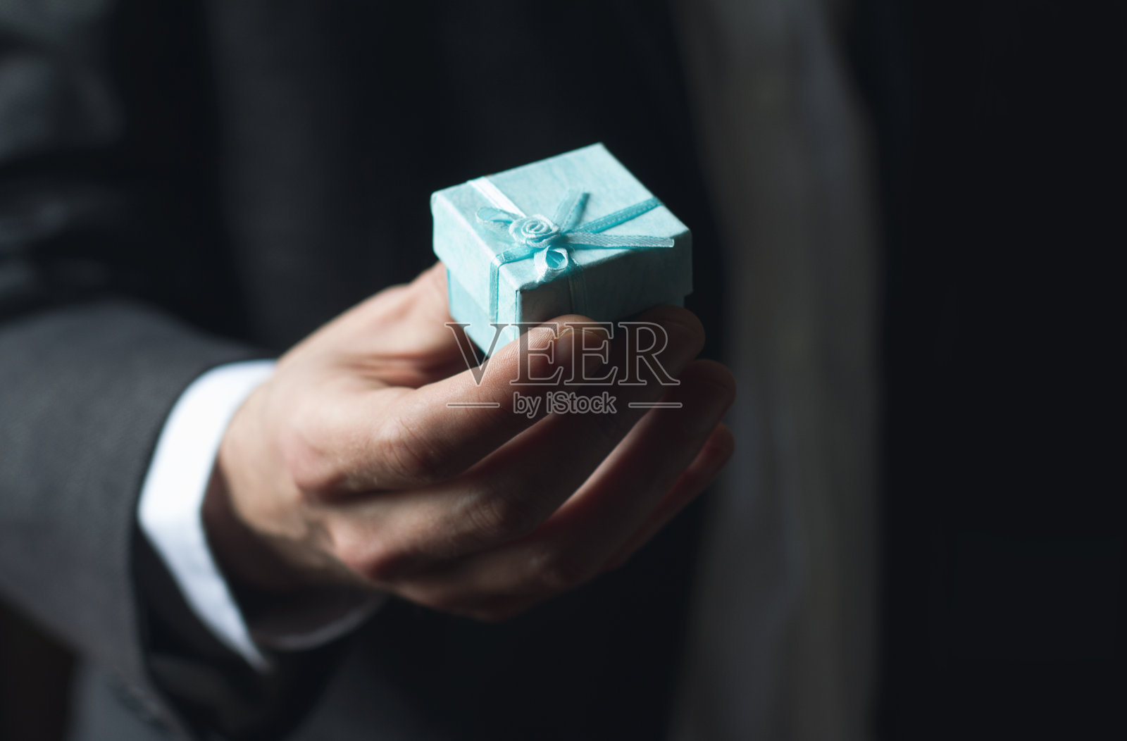 男子献上带着蓝丝带的礼物照片摄影图片