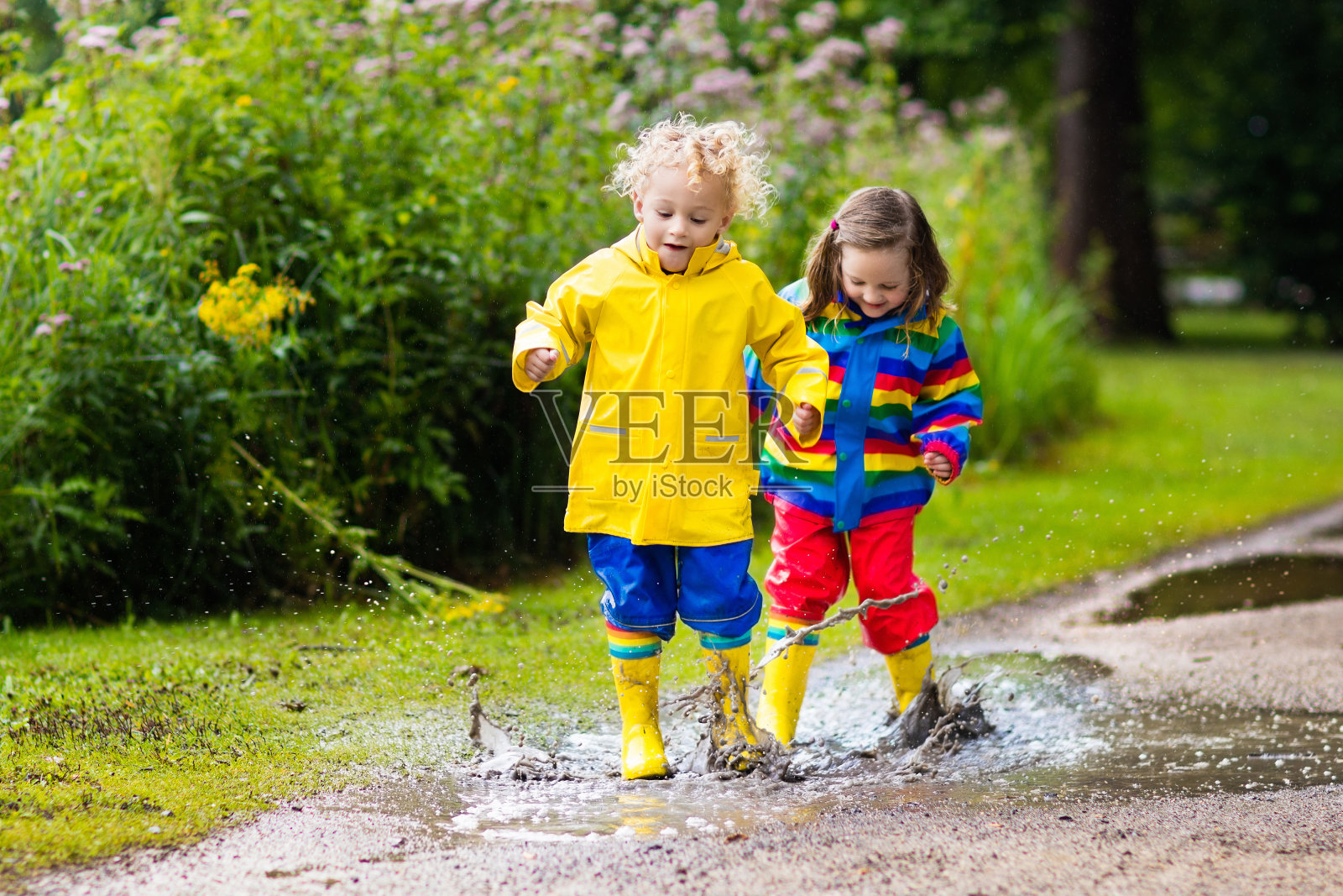 秋天，孩子们在雨中和水坑里玩耍照片摄影图片
