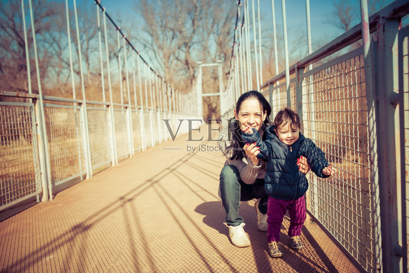 年轻的母亲和小女儿在人行桥上玩耍照片摄影图片
