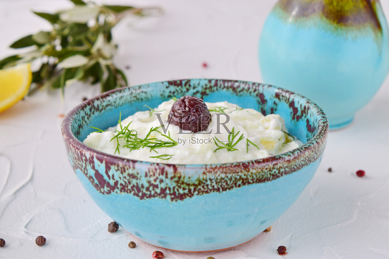 用黄瓜、大蒜、酸奶、橄榄油和柠檬在白色背景的传统彩色碗里自制希腊传统酱汁酸奶黄瓜。健康饮食的概念。地中海的生活方式照片摄影图片