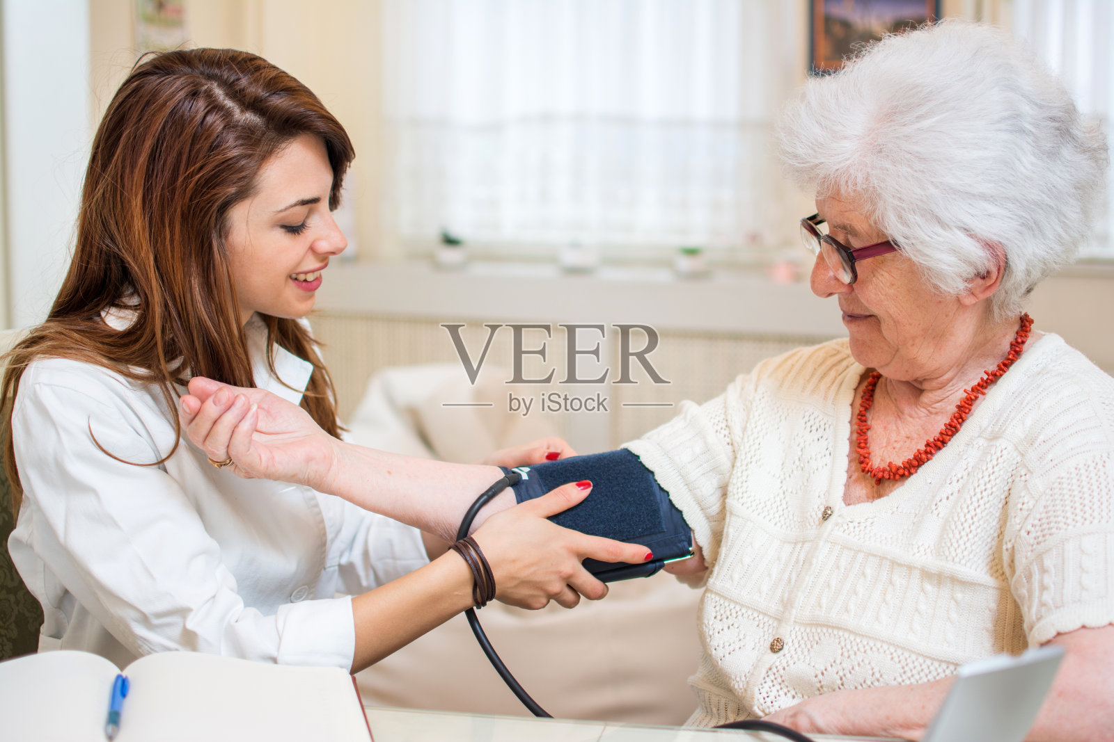护士在家为老年妇女做血压监测。照片摄影图片