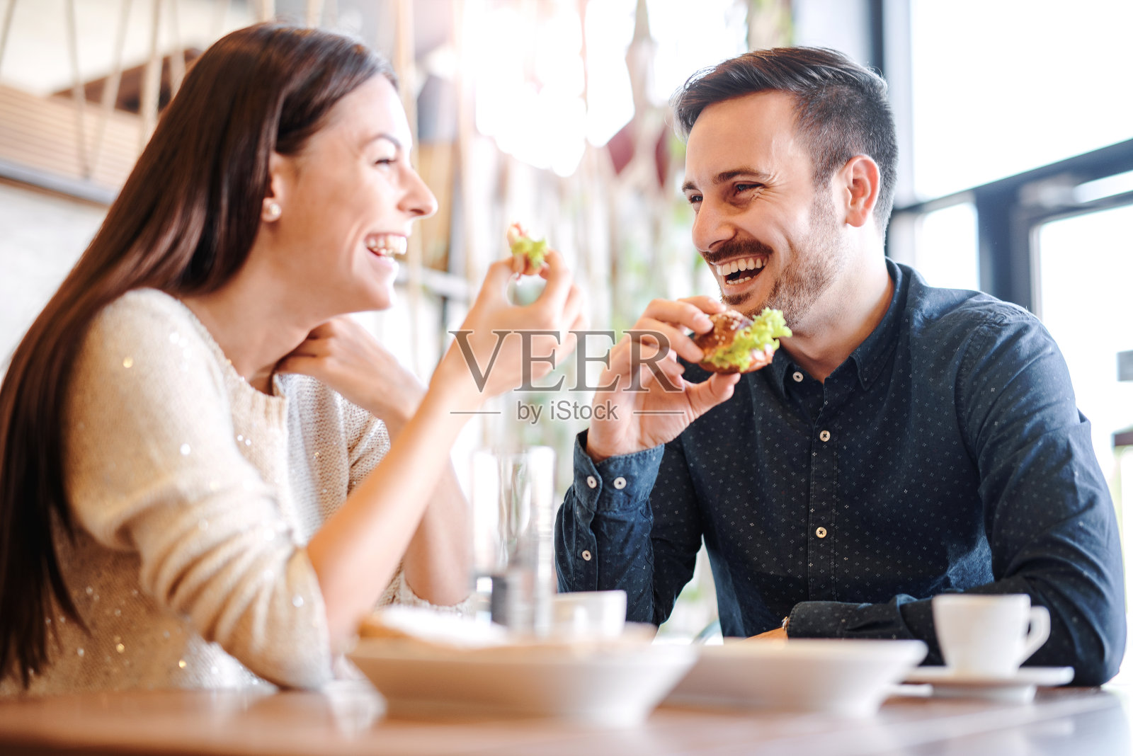 一对年轻漂亮的夫妇坐在咖啡馆里吃早餐。爱,食物,生活方式照片摄影图片