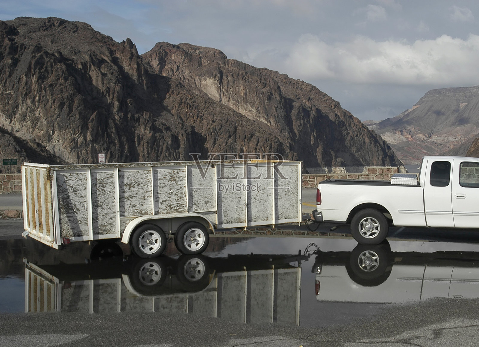 卡车和拖车停在山麓的一个大水坑里照片摄影图片