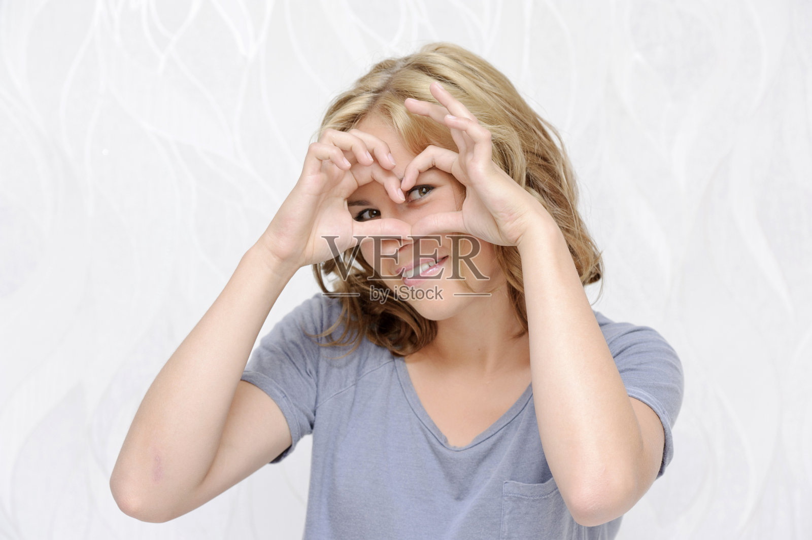 微笑的年轻女子用手指做心照片摄影图片