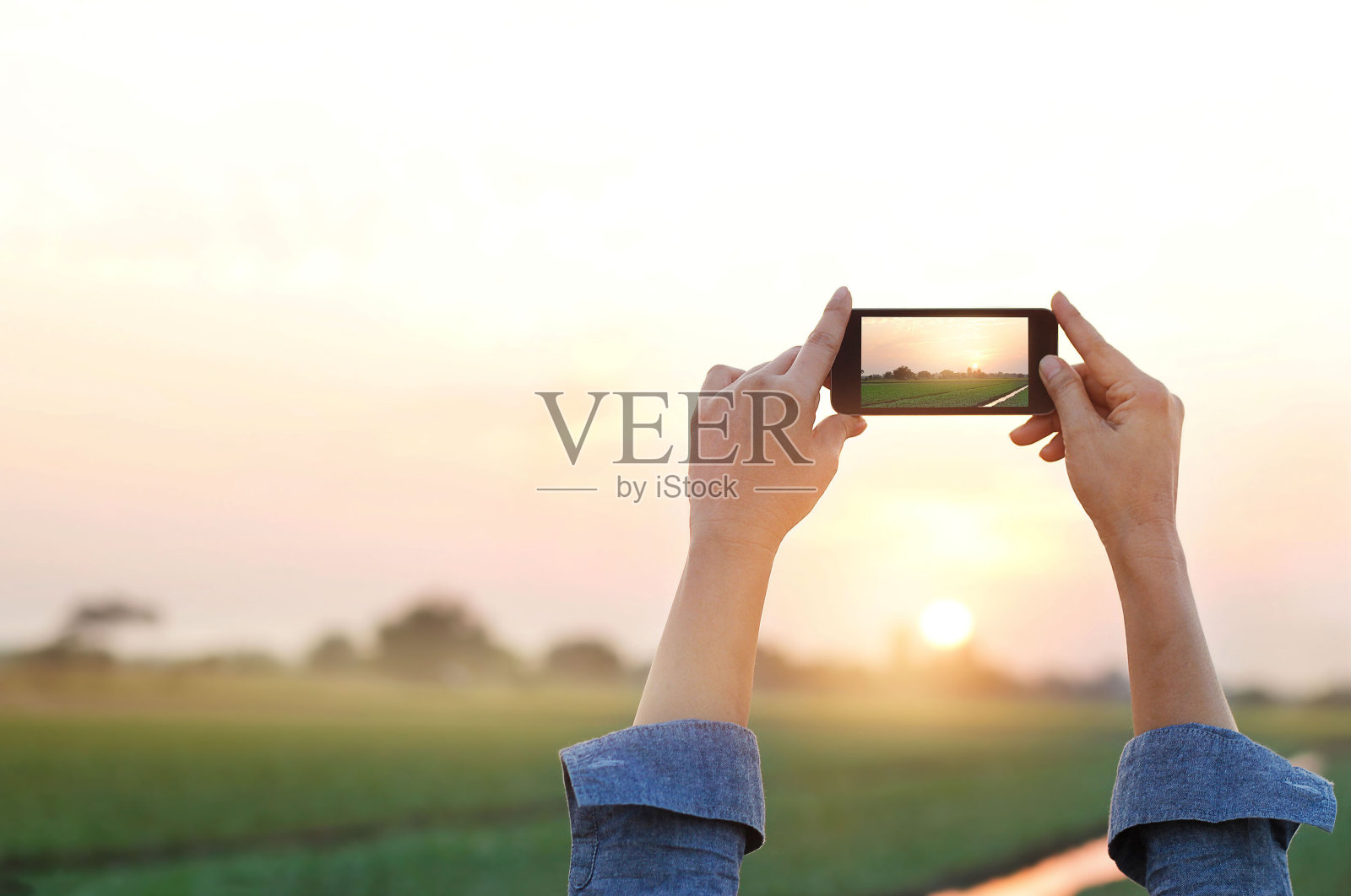 女人在夕阳下拍摄田园草原，放松时光照片摄影图片