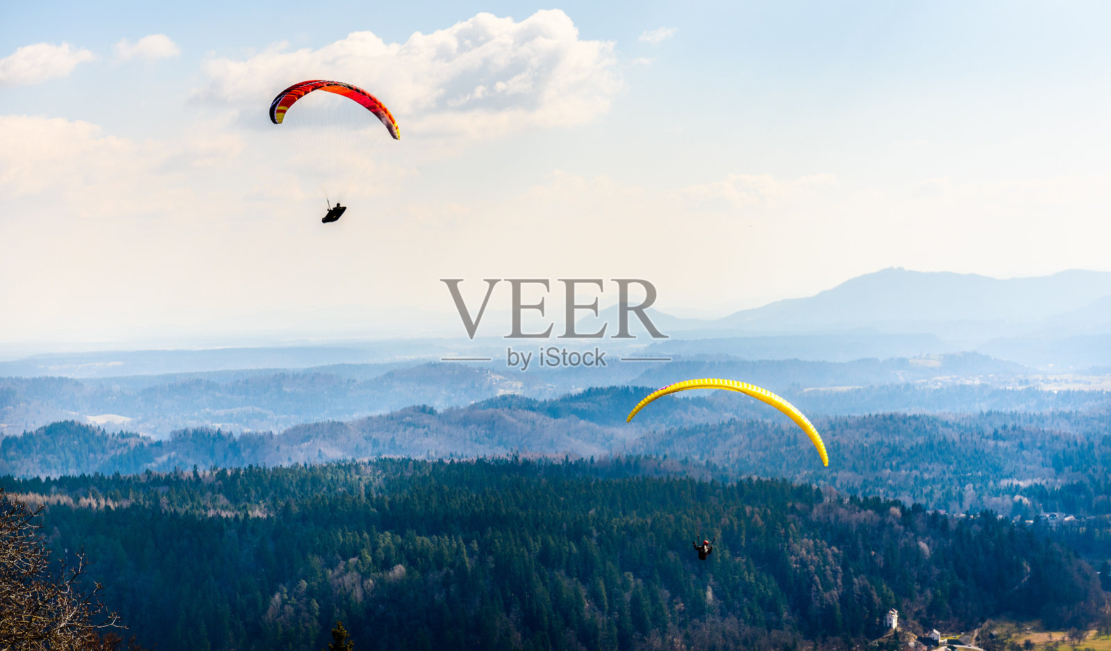 两个滑翔伞在山谷中飞行。照片摄影图片