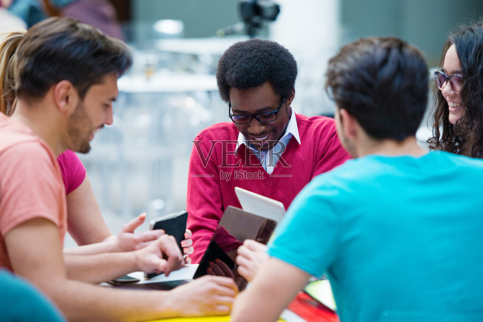 多种族的年轻学生一起学习。年轻人坐在桌子旁的高角度镜头。照片摄影图片