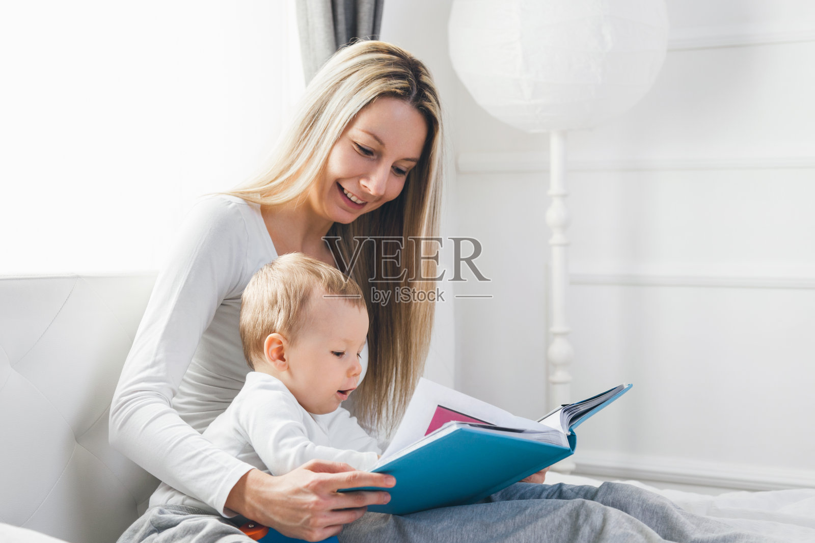 孩子的教育。快乐的妈妈和她的孩子坐在床上看书照片摄影图片
