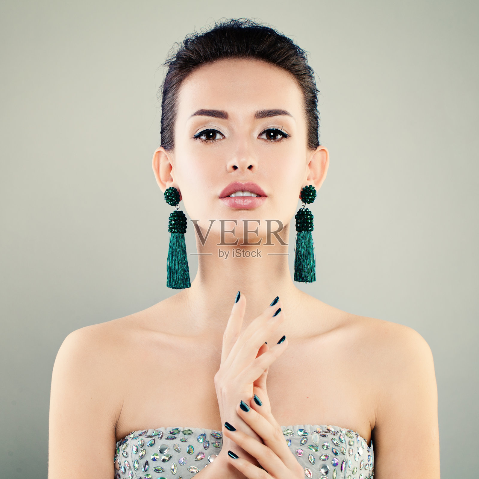美丽的模特女人化妆，美甲和绿色耳环。可爱的年轻的脸照片摄影图片