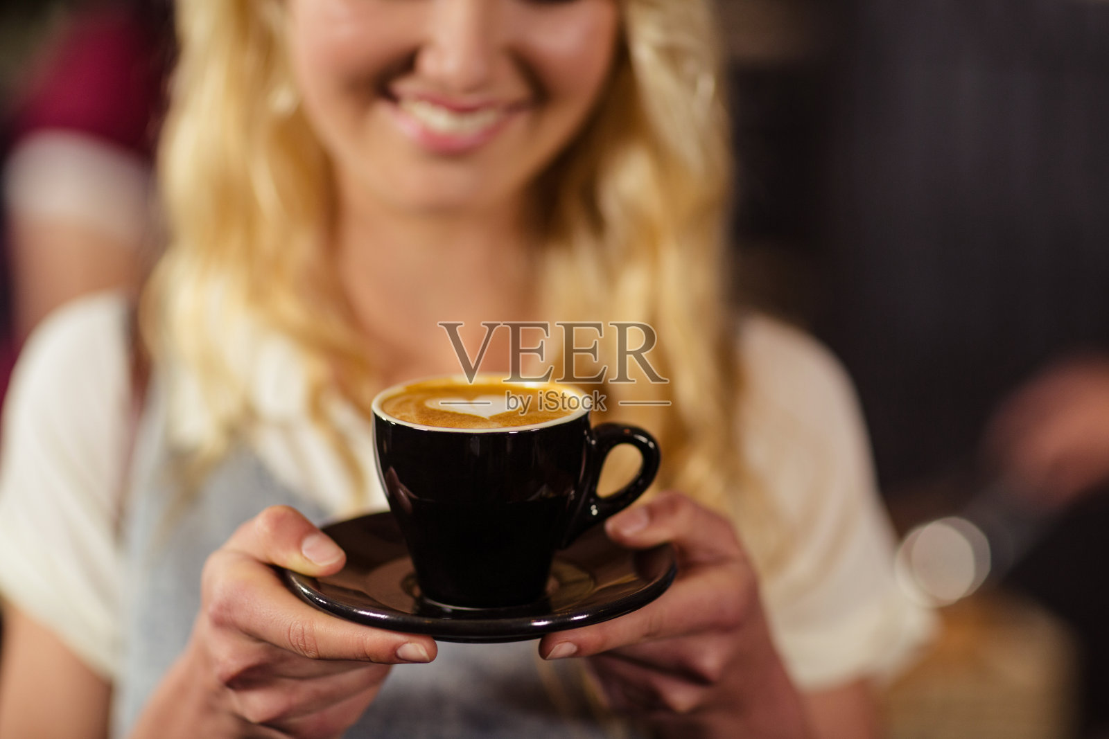 微笑的漂亮的顾客捧着一杯咖啡的肖像照片摄影图片