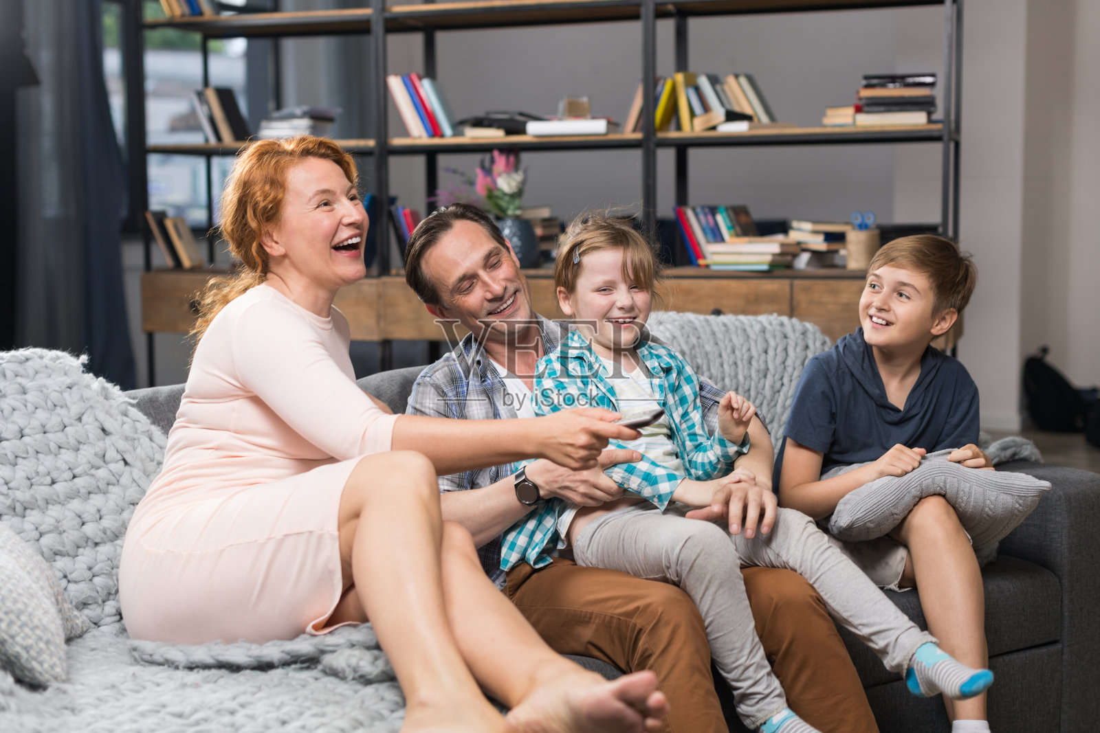一家人坐在沙发上看电视，快乐的父母花时间与孩子在一起照片摄影图片