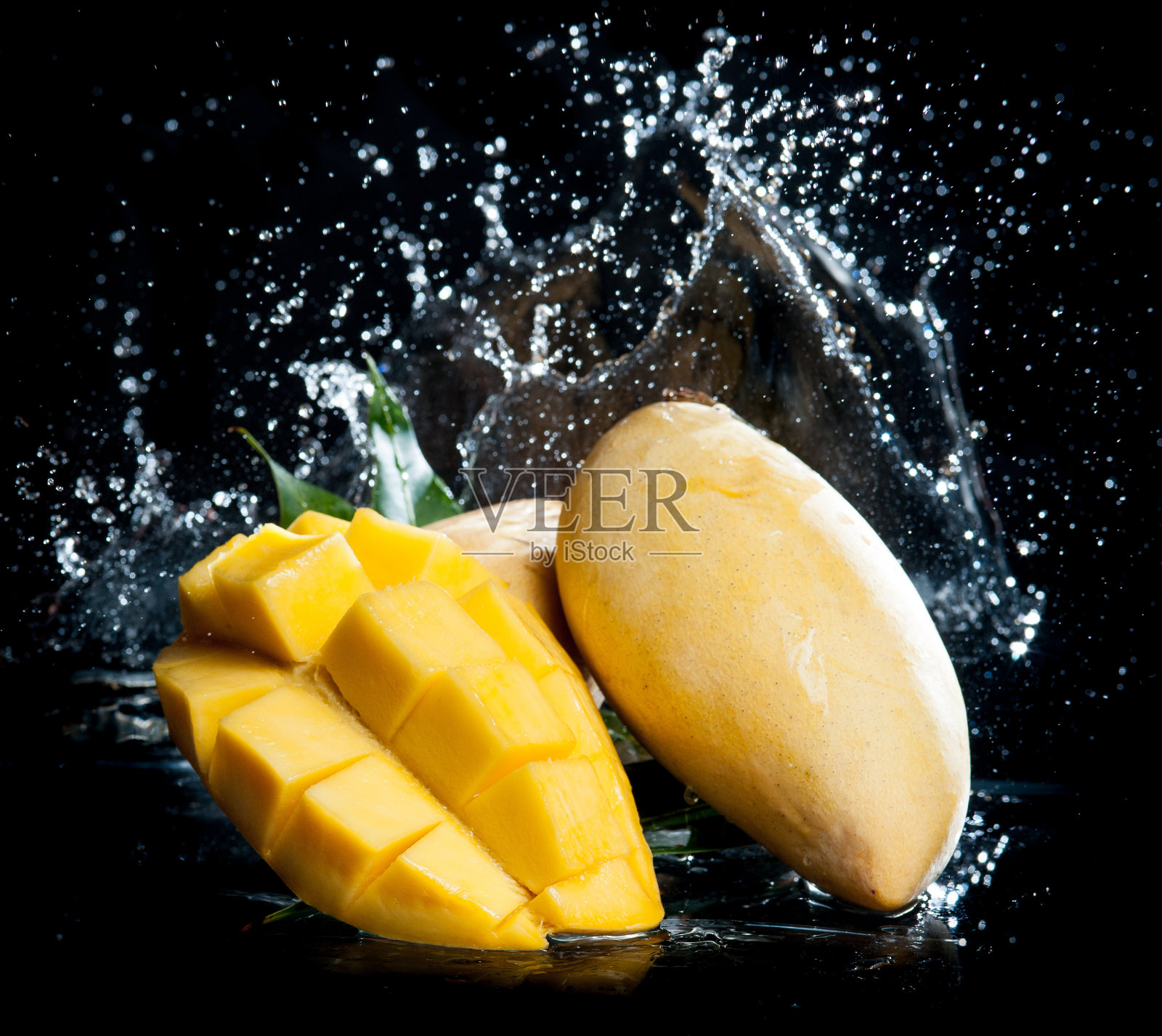 芒果溅在清澈的水在黑色的背景照片摄影图片