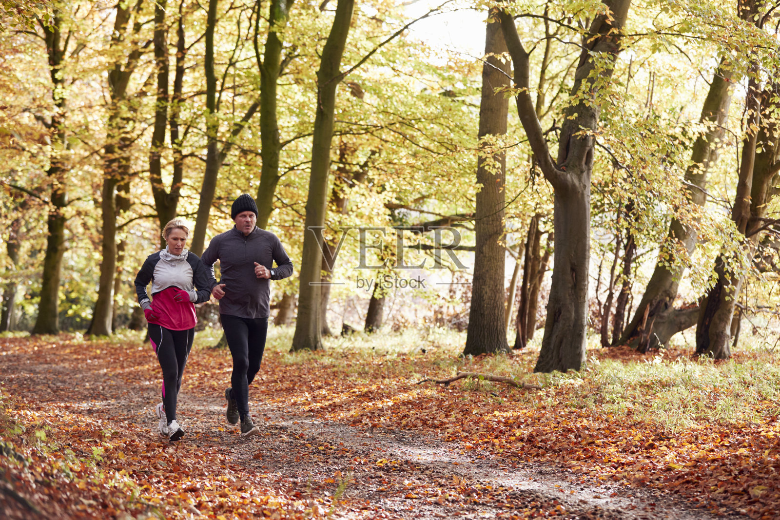 成熟的夫妇一起跑过秋天的林地照片摄影图片
