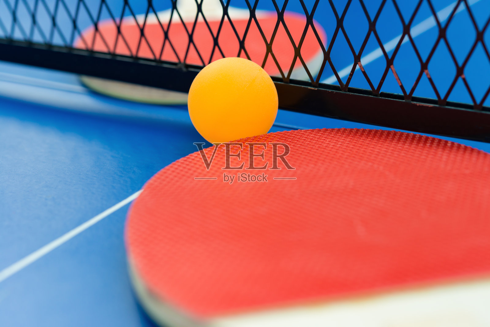乒乓球拍、球和网放在一张蓝色的乒乓球桌上照片摄影图片