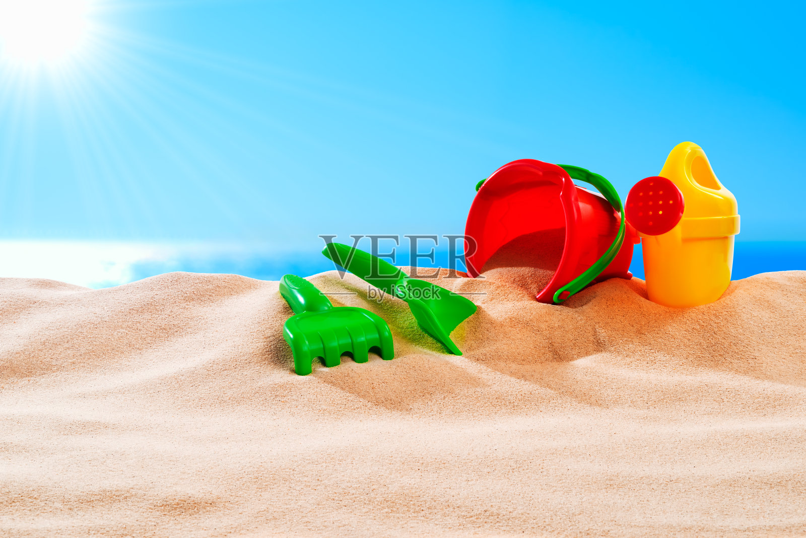 在一个阳光明媚的日子里，在美丽的蔚蓝大海前的一个沙丘上玩沙子的玩具照片摄影图片